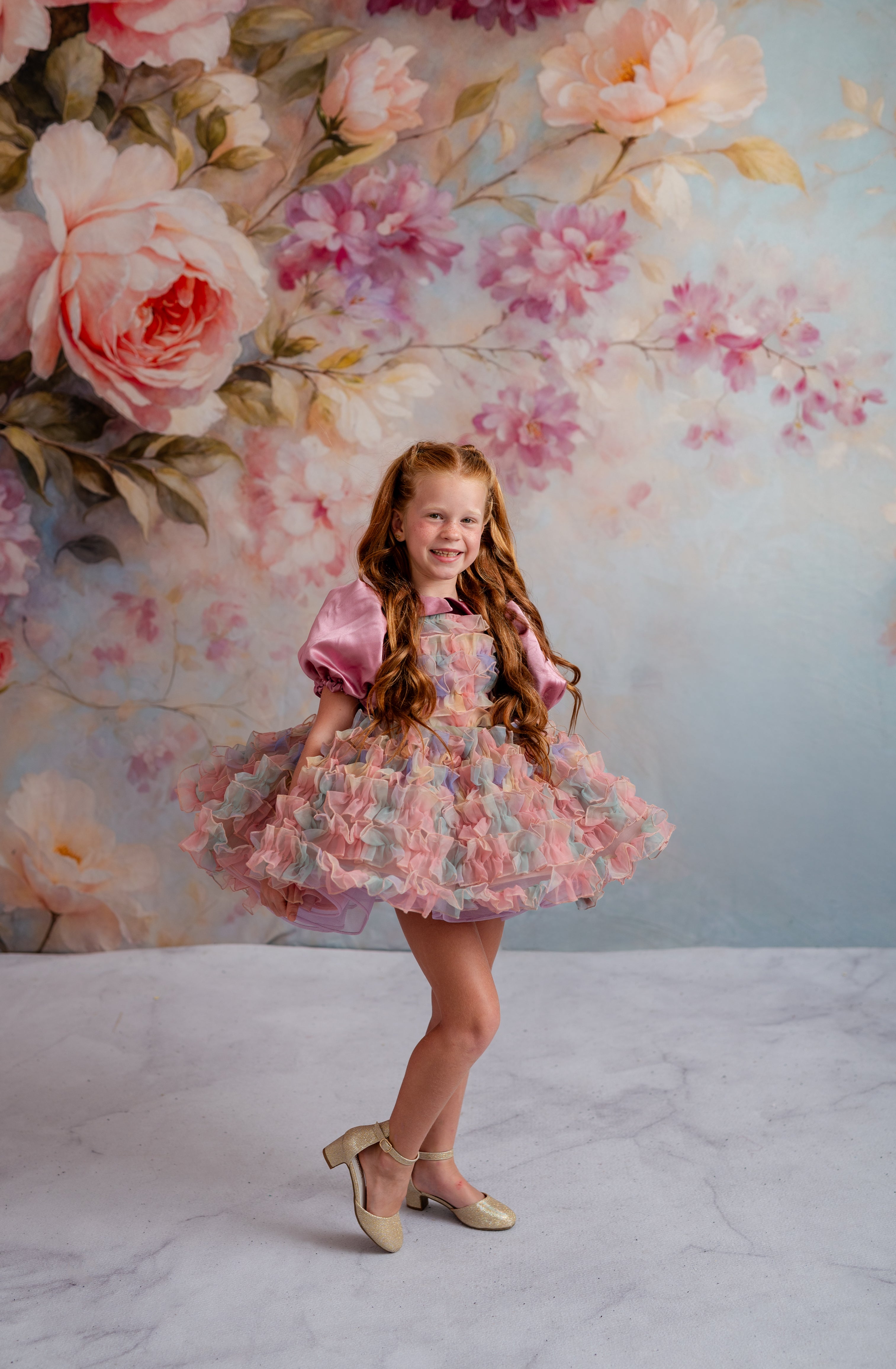Young girl in a floral dress standing in front of a floral backdrop