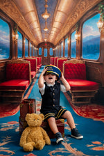 Child in a train car with red seats and a teddy bear, wearing a pilot outfit.