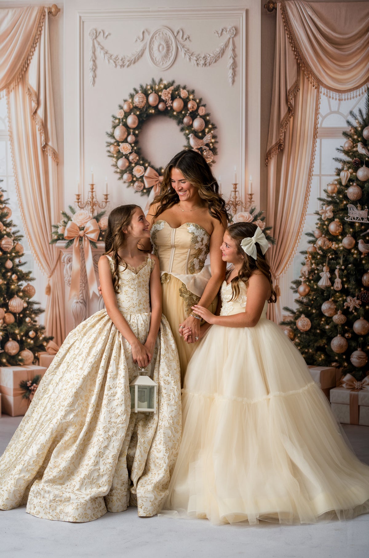 Woman and two young girls in formal dresses standing in a decorated room with Christmas trees and wreaths.