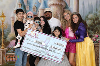 A smiling family posing together during a Leia's Kids event sponsored by Bentley + Lace, surrounded by balloons and decorations.