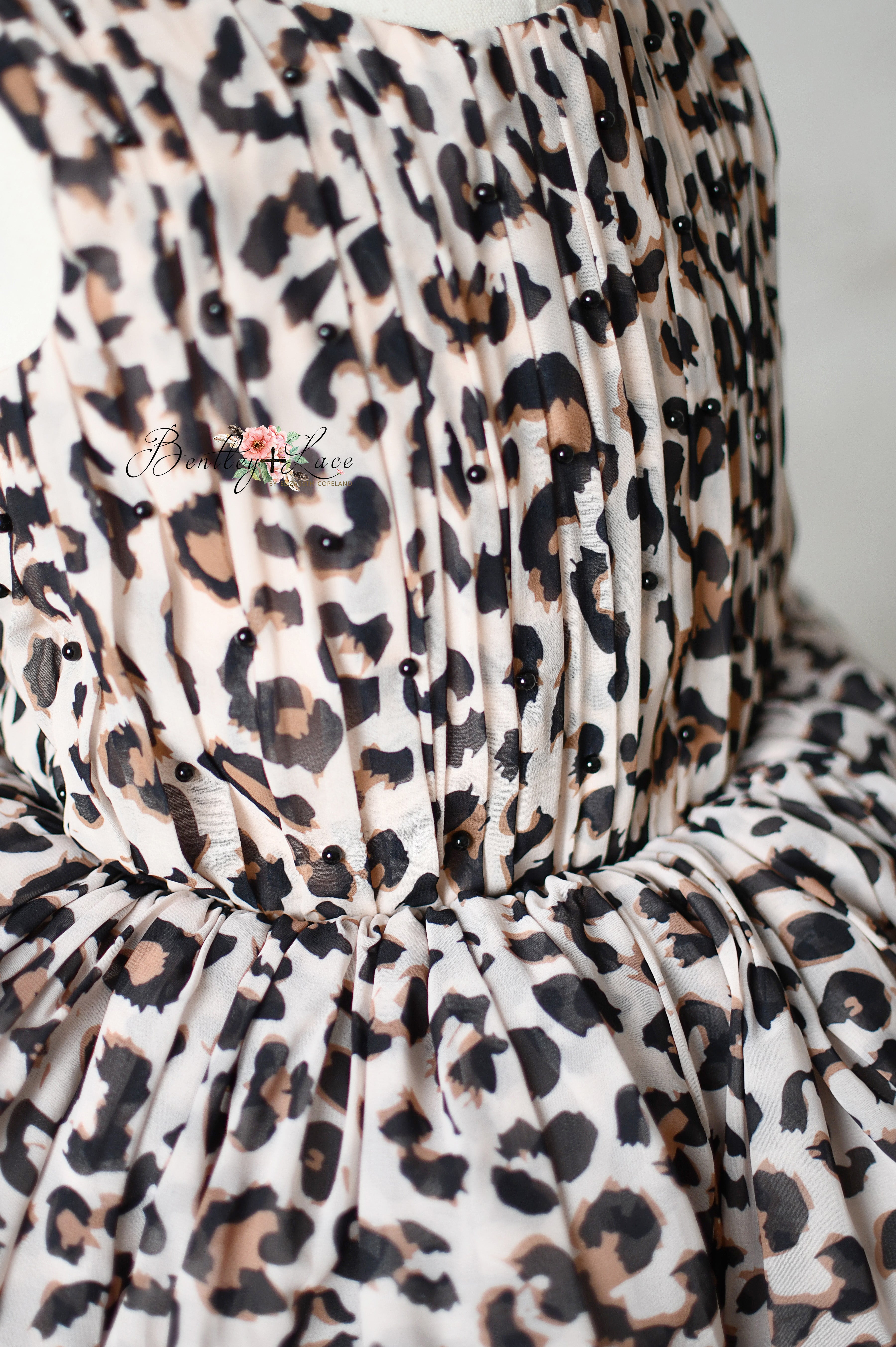 "Back view of a leopard print dress with tie-back details and elastic waist."
