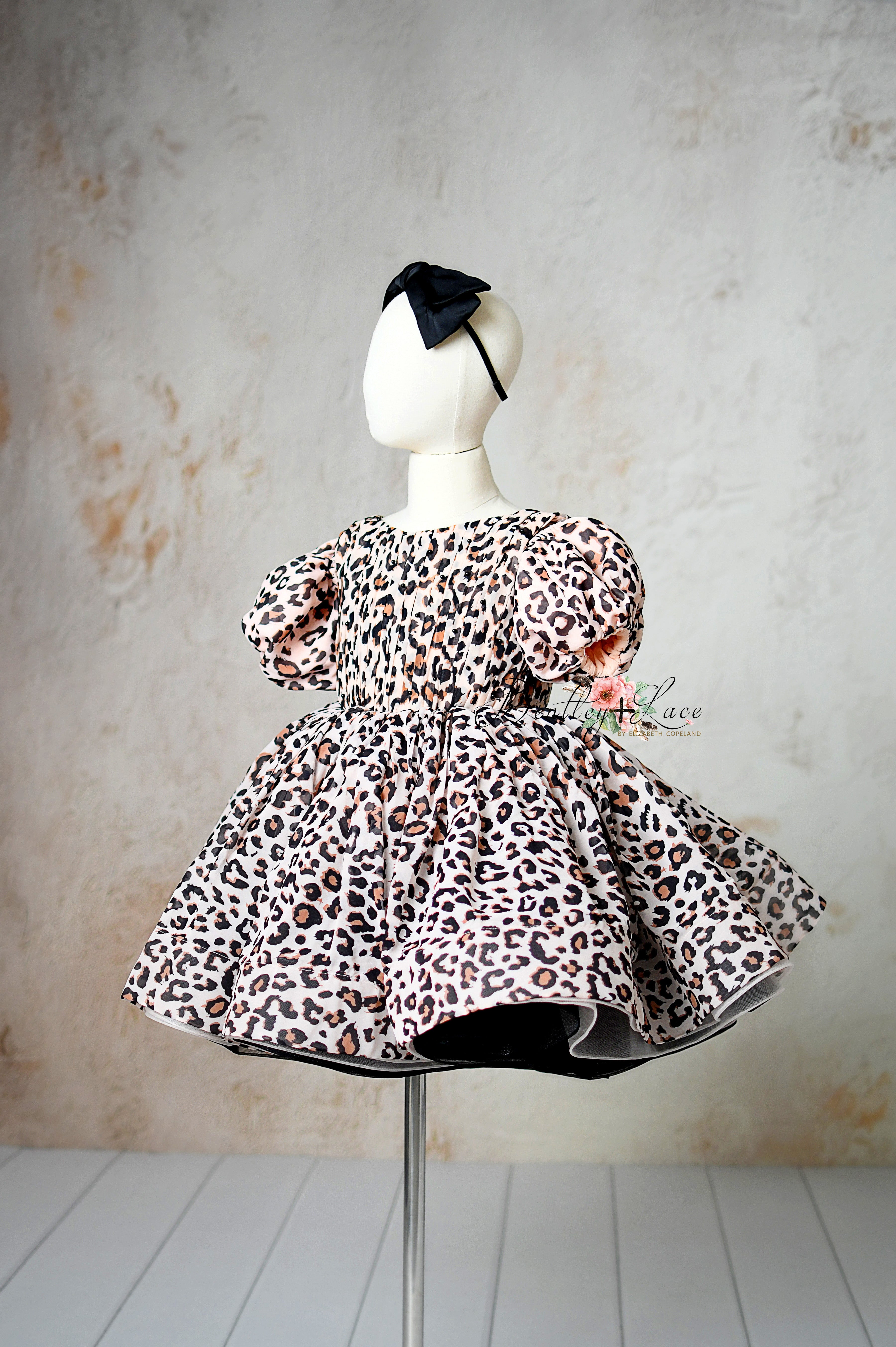 "Close-up of adjustable tie-back waist on a stylish leopard print girls’ dress."
