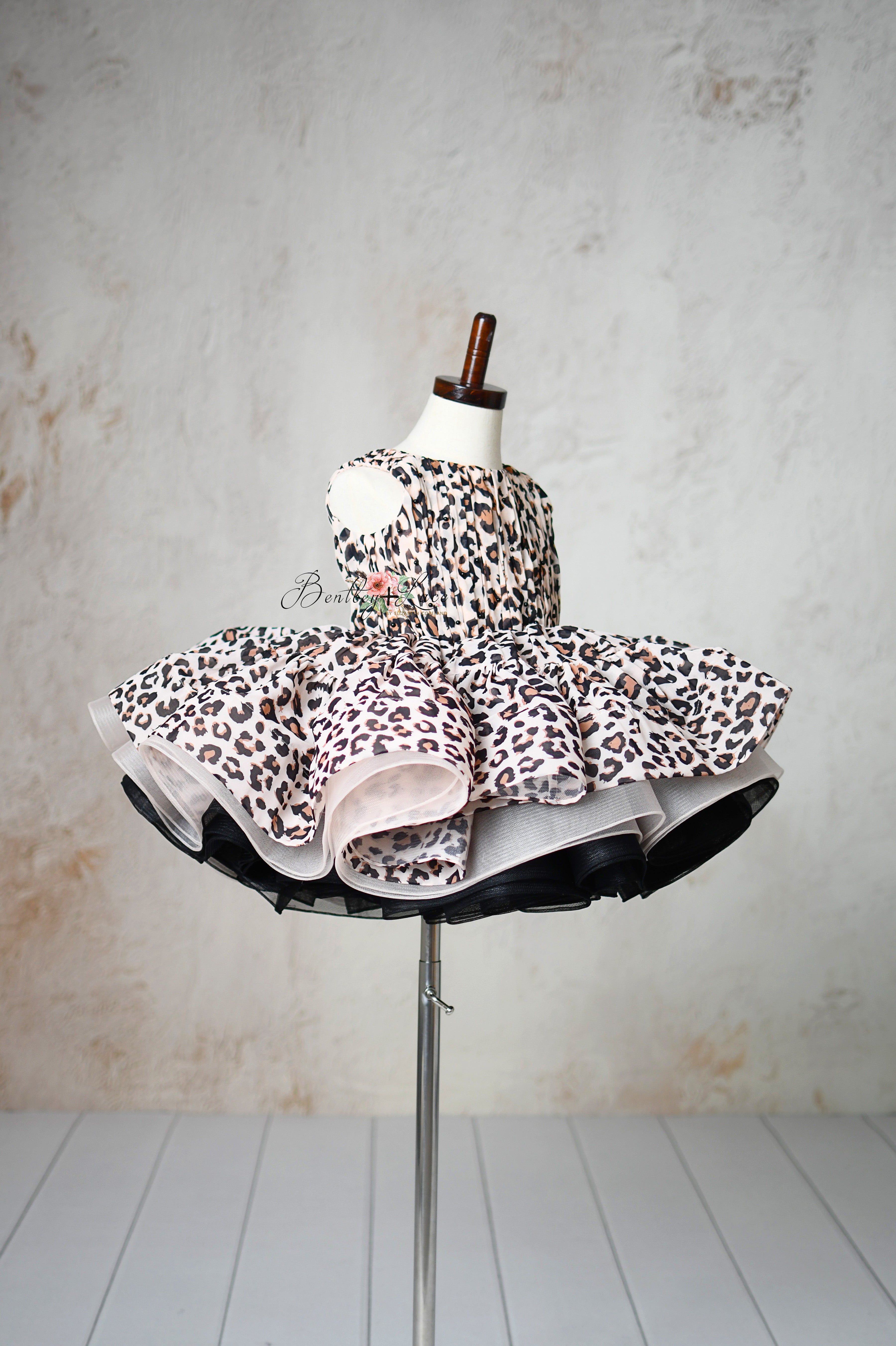 "Close-up of a leopard print dress with puff sleeves and twirl-worthy petal-length design for toddlers."
