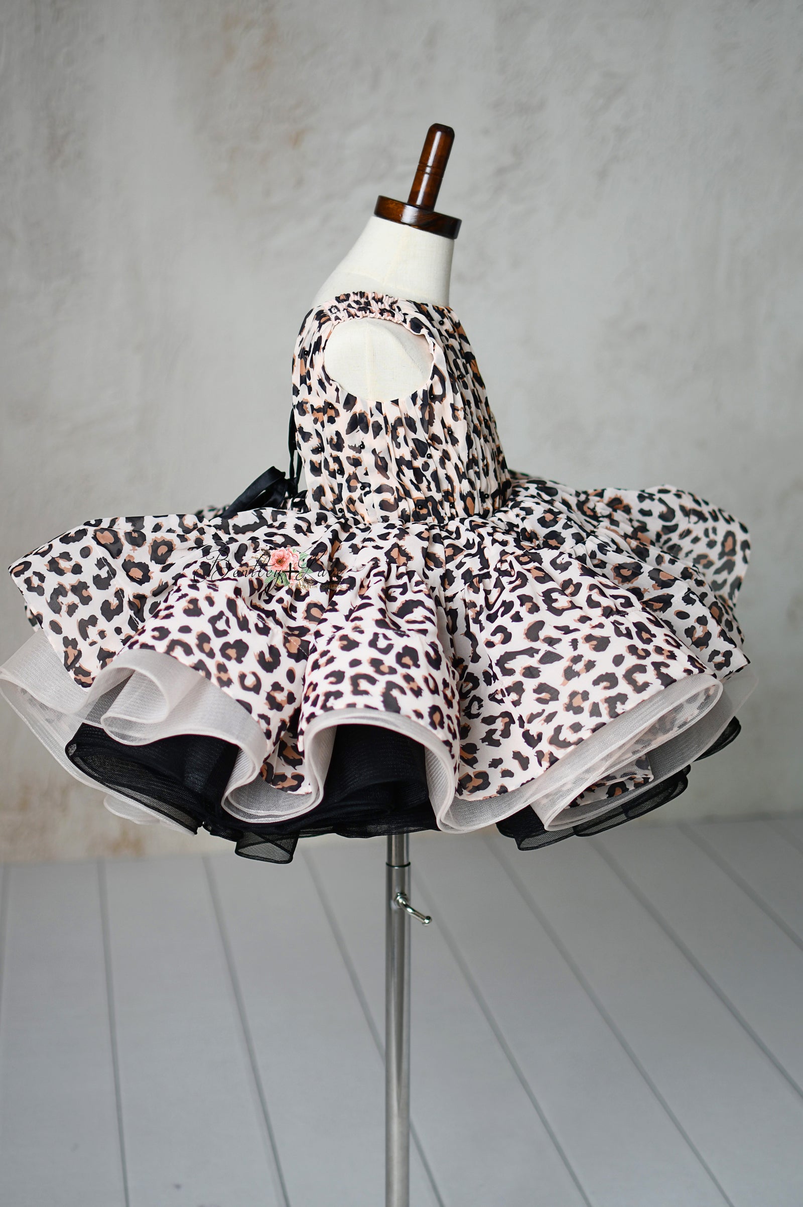 "Detailed view of puff sleeves and leopard print fabric on a toddler petal-length dress."
