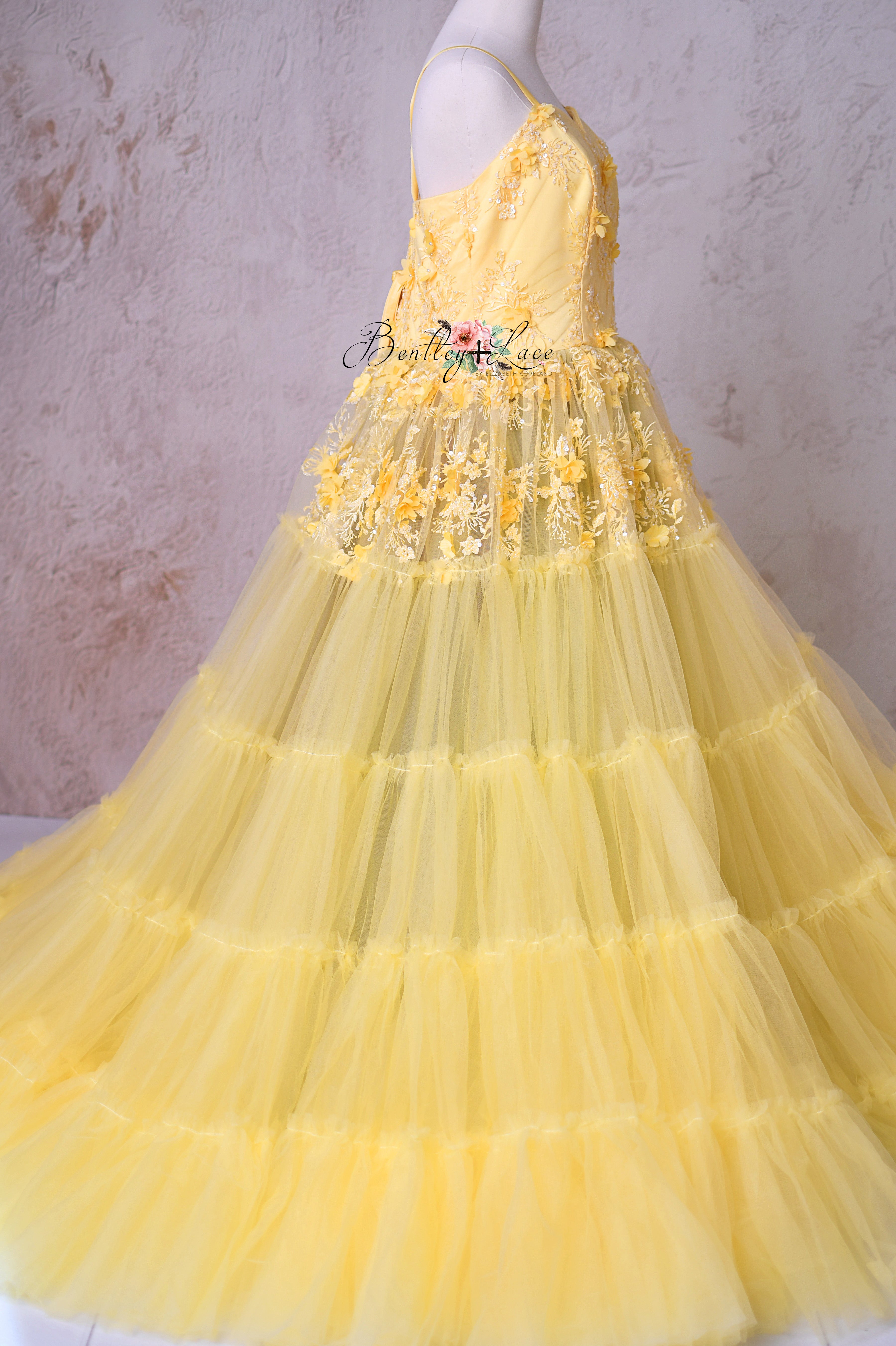 Side view of the Buttercup gown, displaying its voluminous layered tulle and elegant silhouette.
