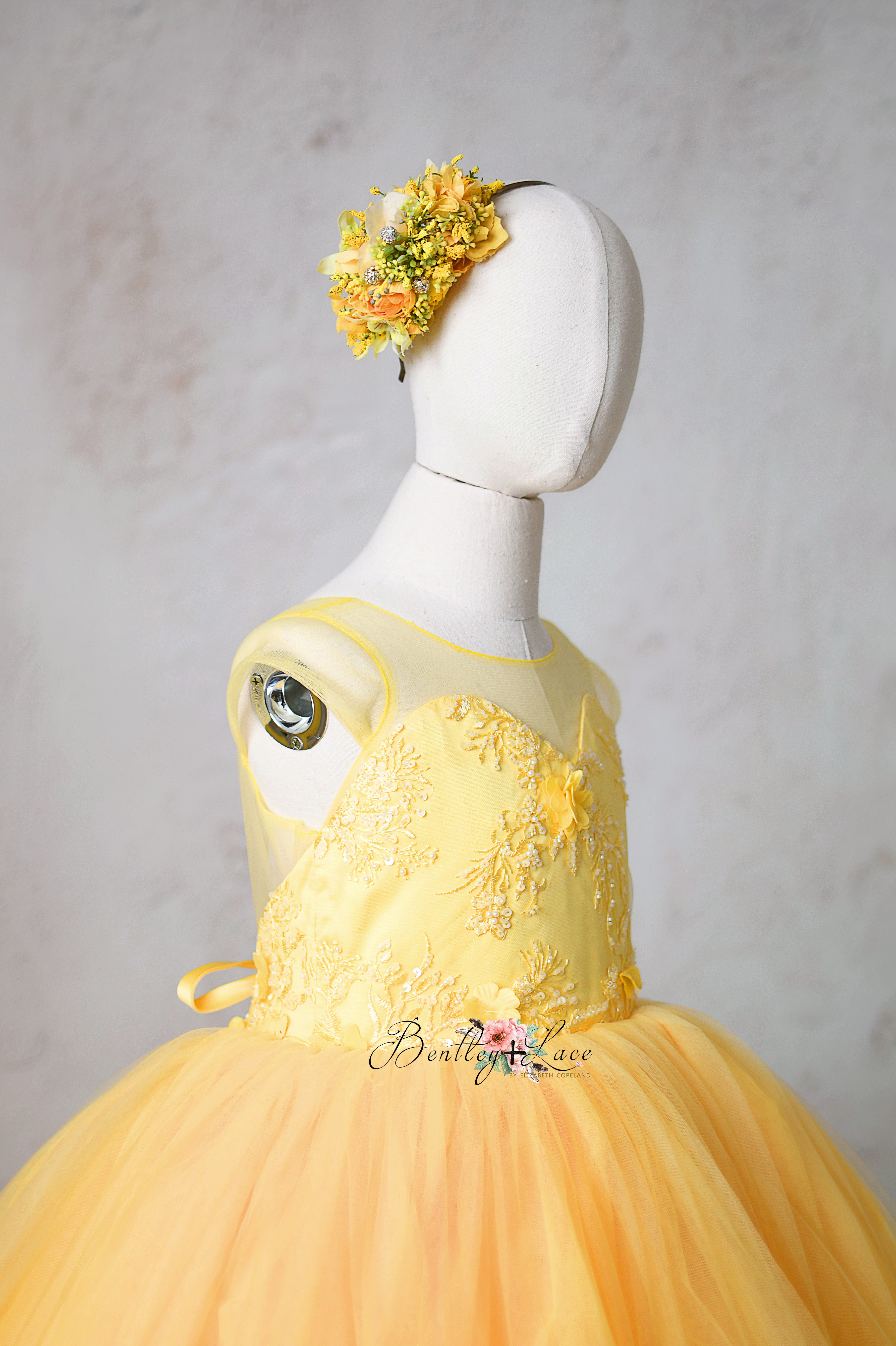 The Buttercup gown features an elegant closed-shoulder bodice with intricate floral details.
