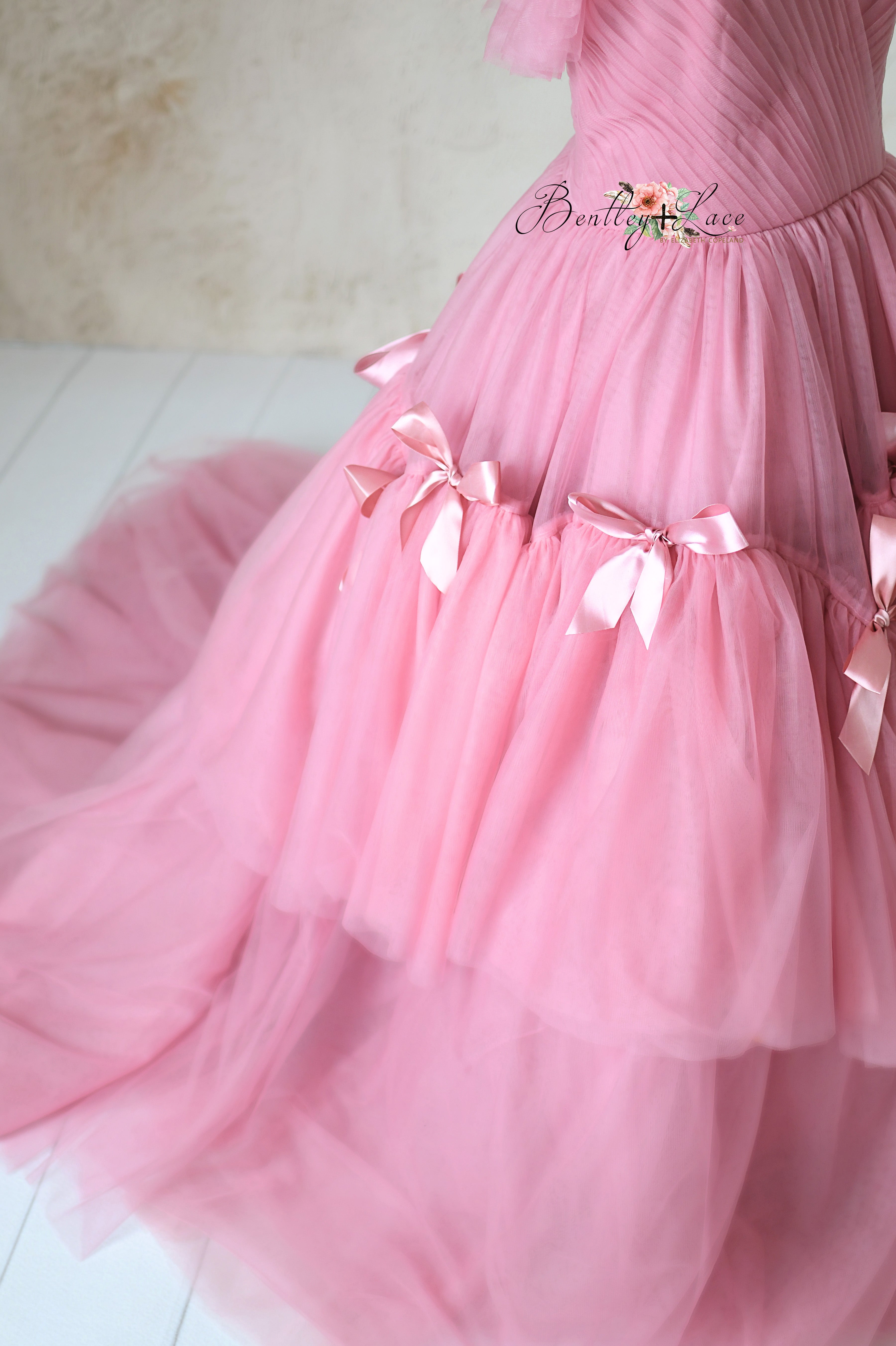 Romantic ball gown featuring cascading tulle and satin ribbon accents.
