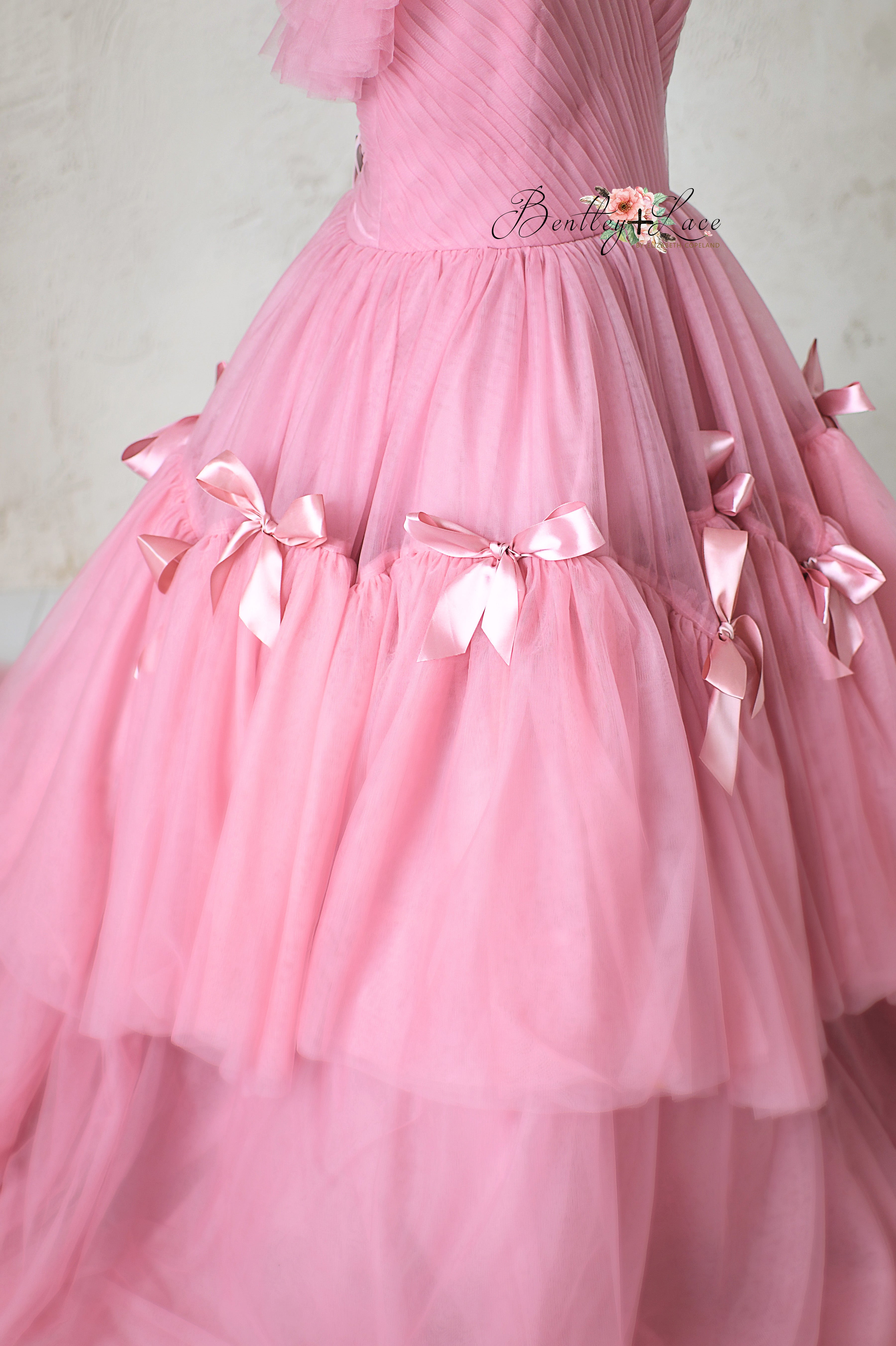 Whimsical pink princess-style gown with flowing layers and soft textures.
