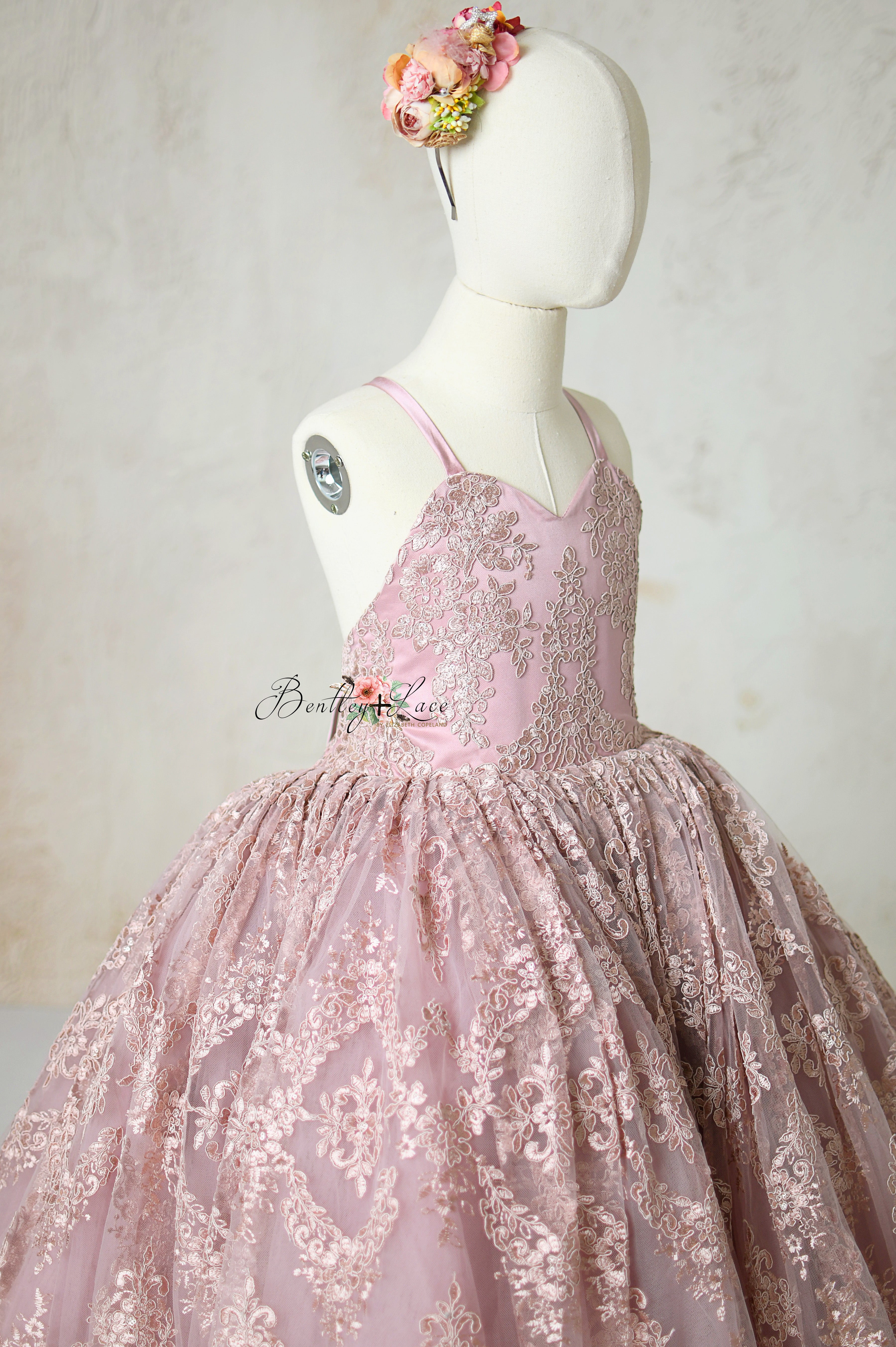 Vintage-inspired mauve gown with a floral waist accent and delicate, scalloped lace edges.
