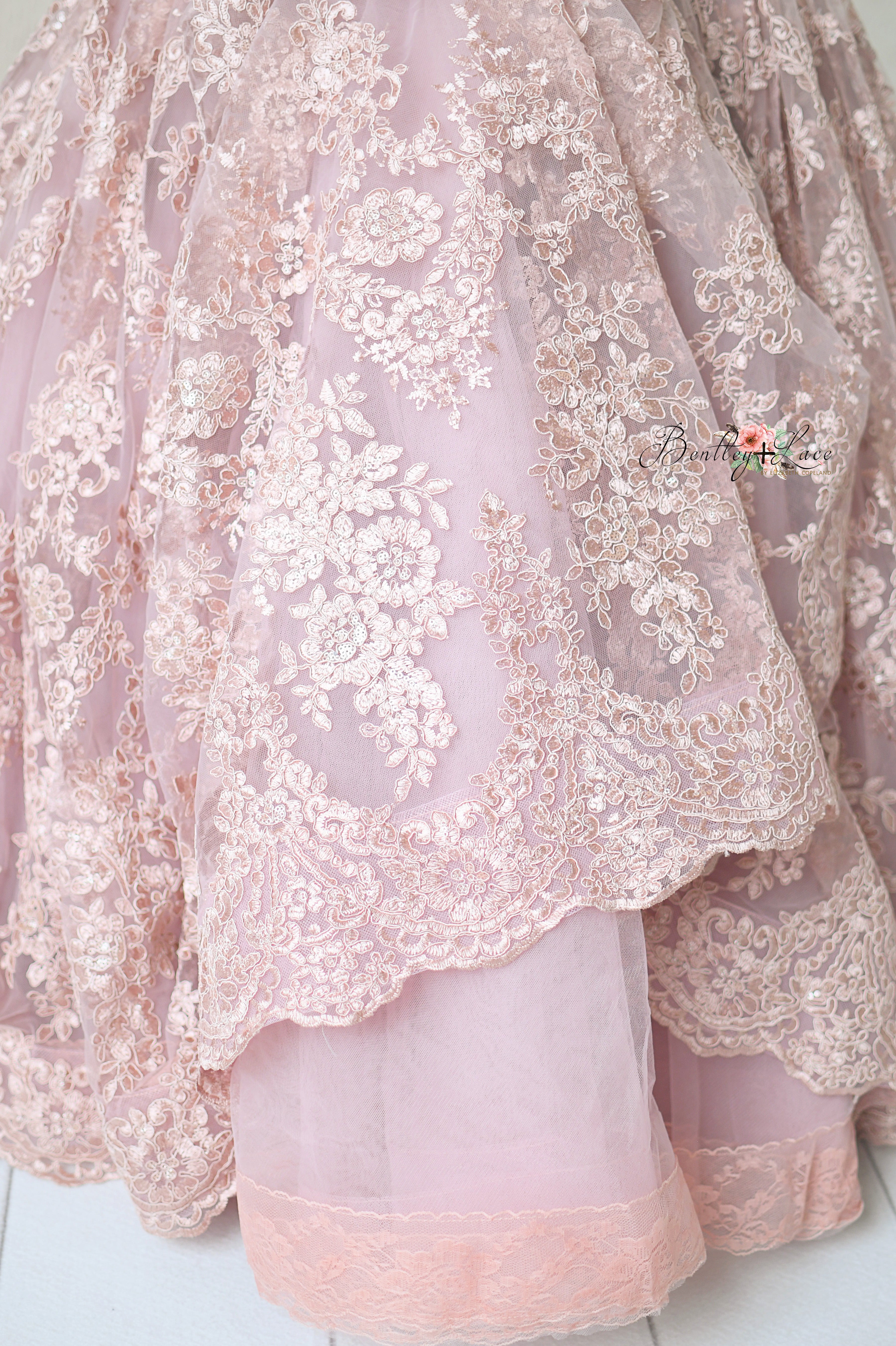 Romantic dusty mauve gown displayed on a mannequin, featuring floral lace and a soft silhouette.
