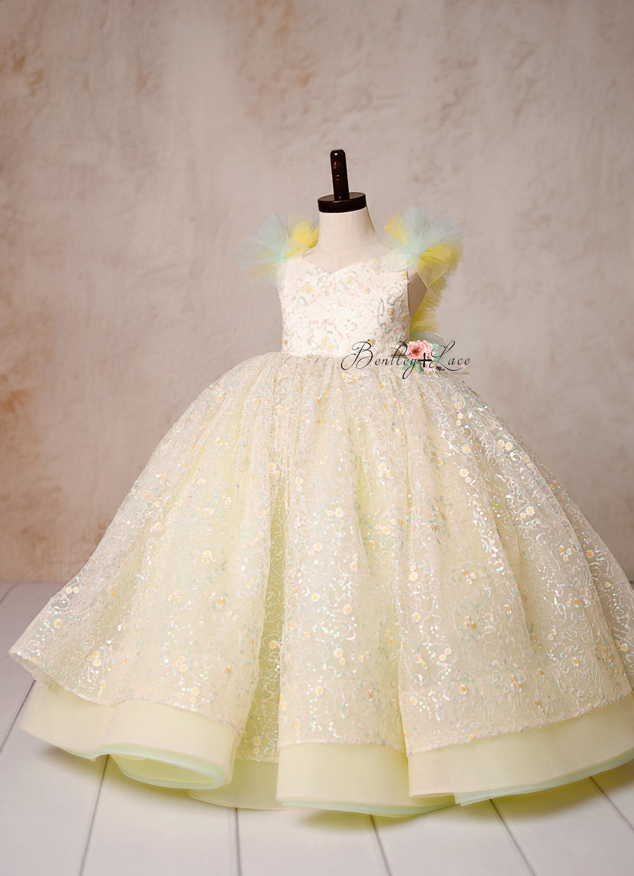 Capture timeless elegance with the Harmony Gown, featuring shimmering daisy lace, pastel hues, and a fairytale-inspired silhouette.

