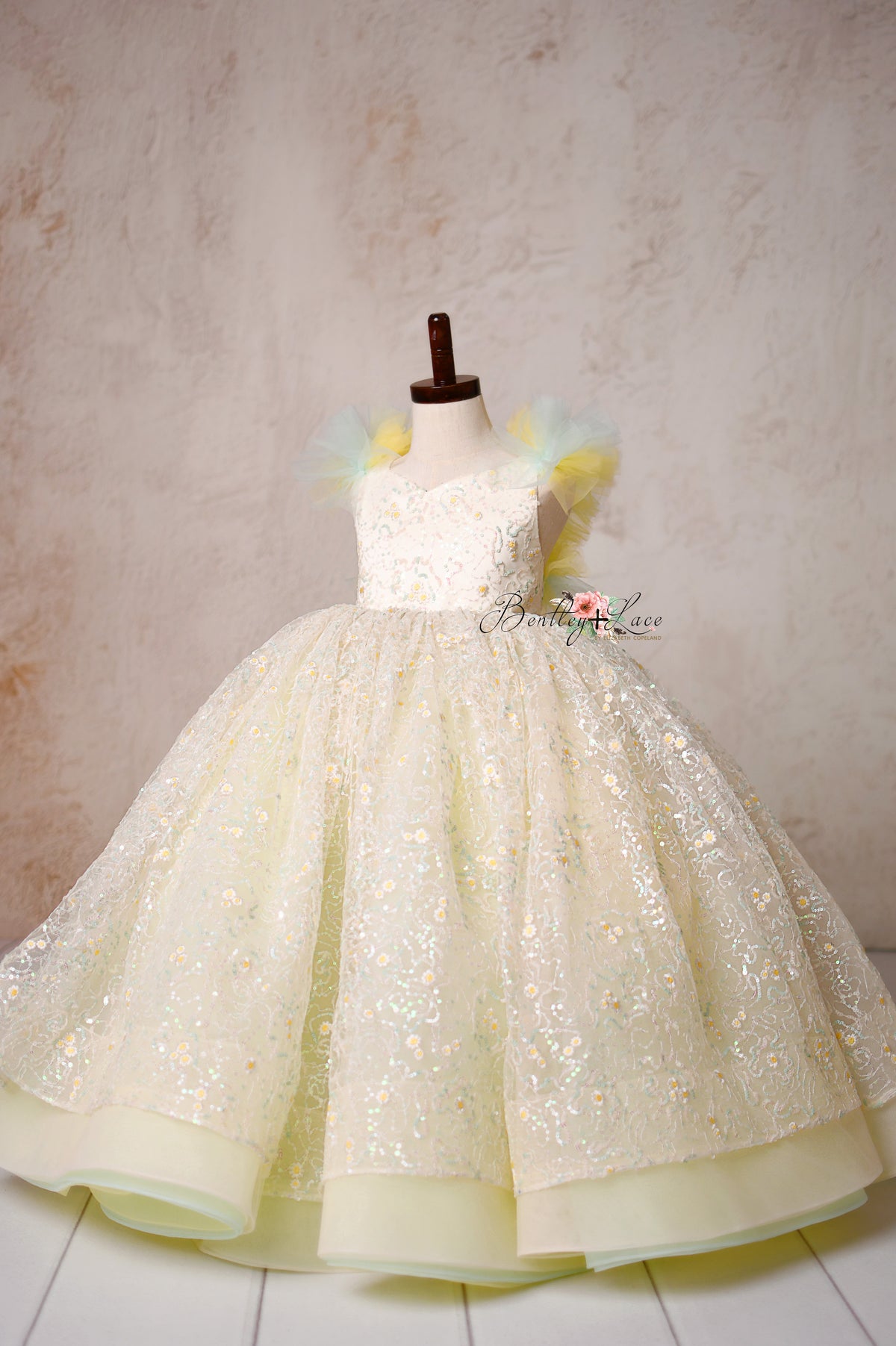 A vision of grace—the Harmony Gown’s soft tulle, intricate floral sequins, and golden shimmer create a picture-perfect look.

