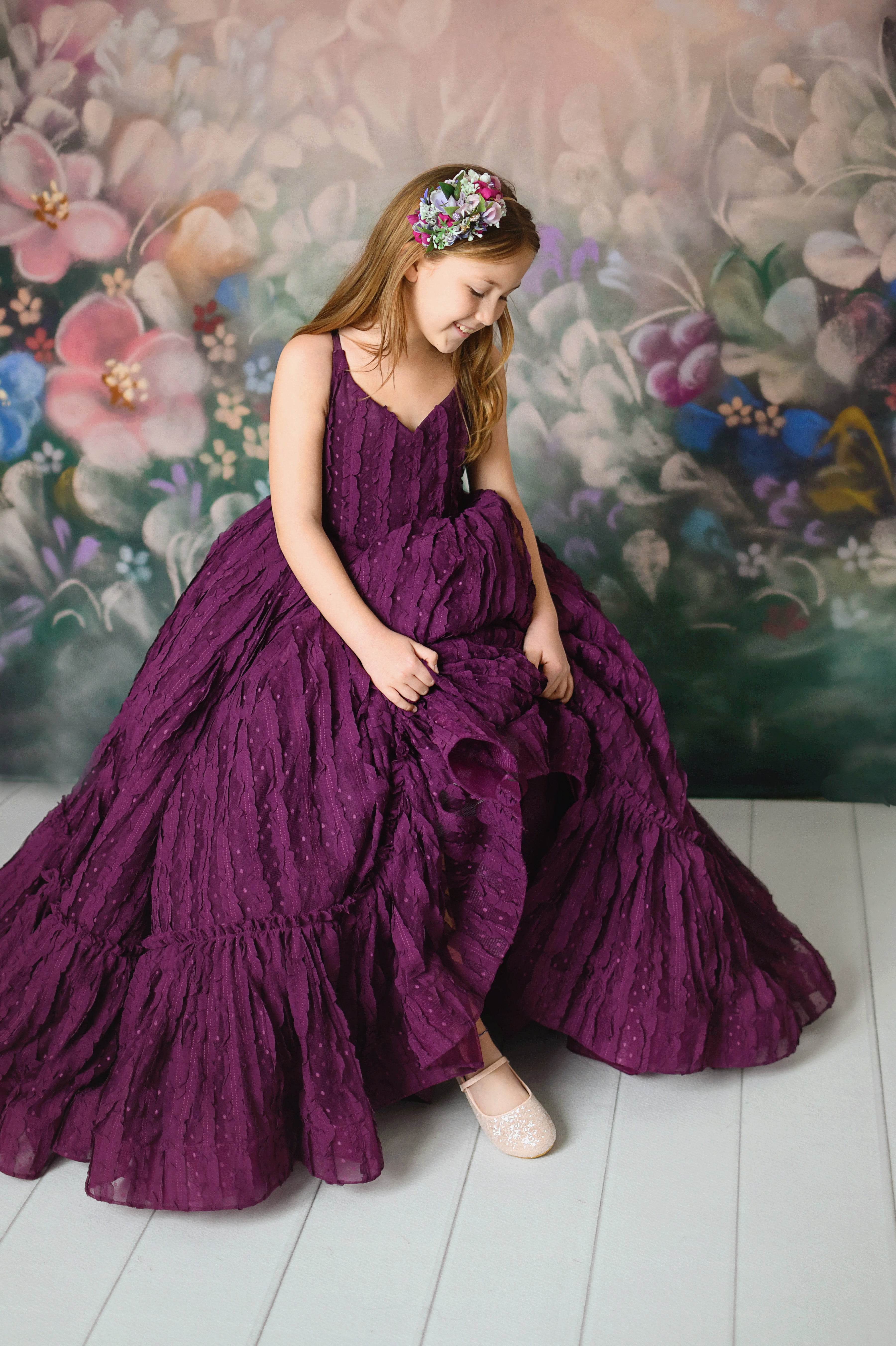 Elegant deep purple gown with textured layers and a flowing silhouette, perfect for photoshoots.
