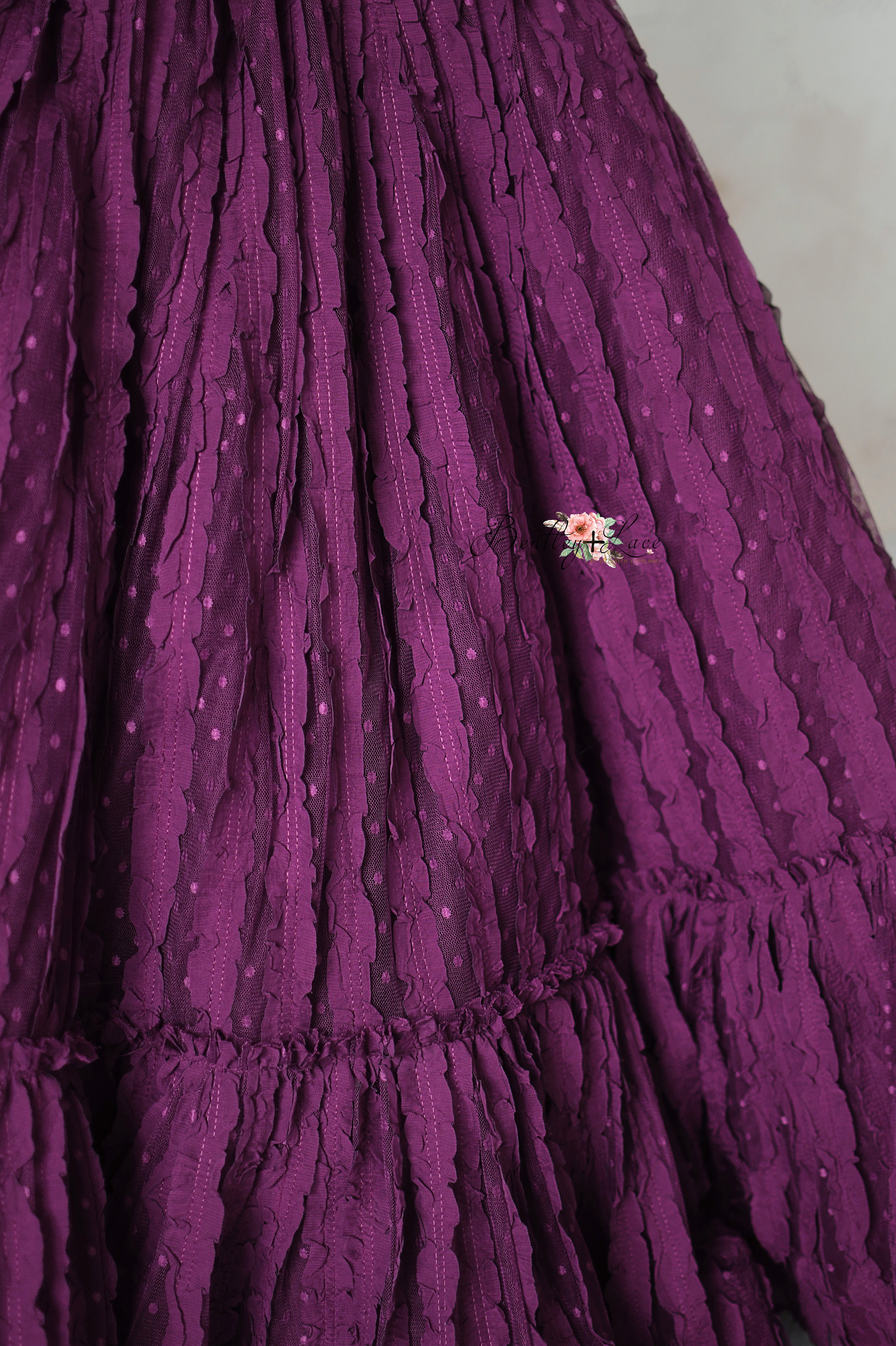 A statement gown in a rich jewel tone, adorned with cascading lace layers and a fitted bodice.
