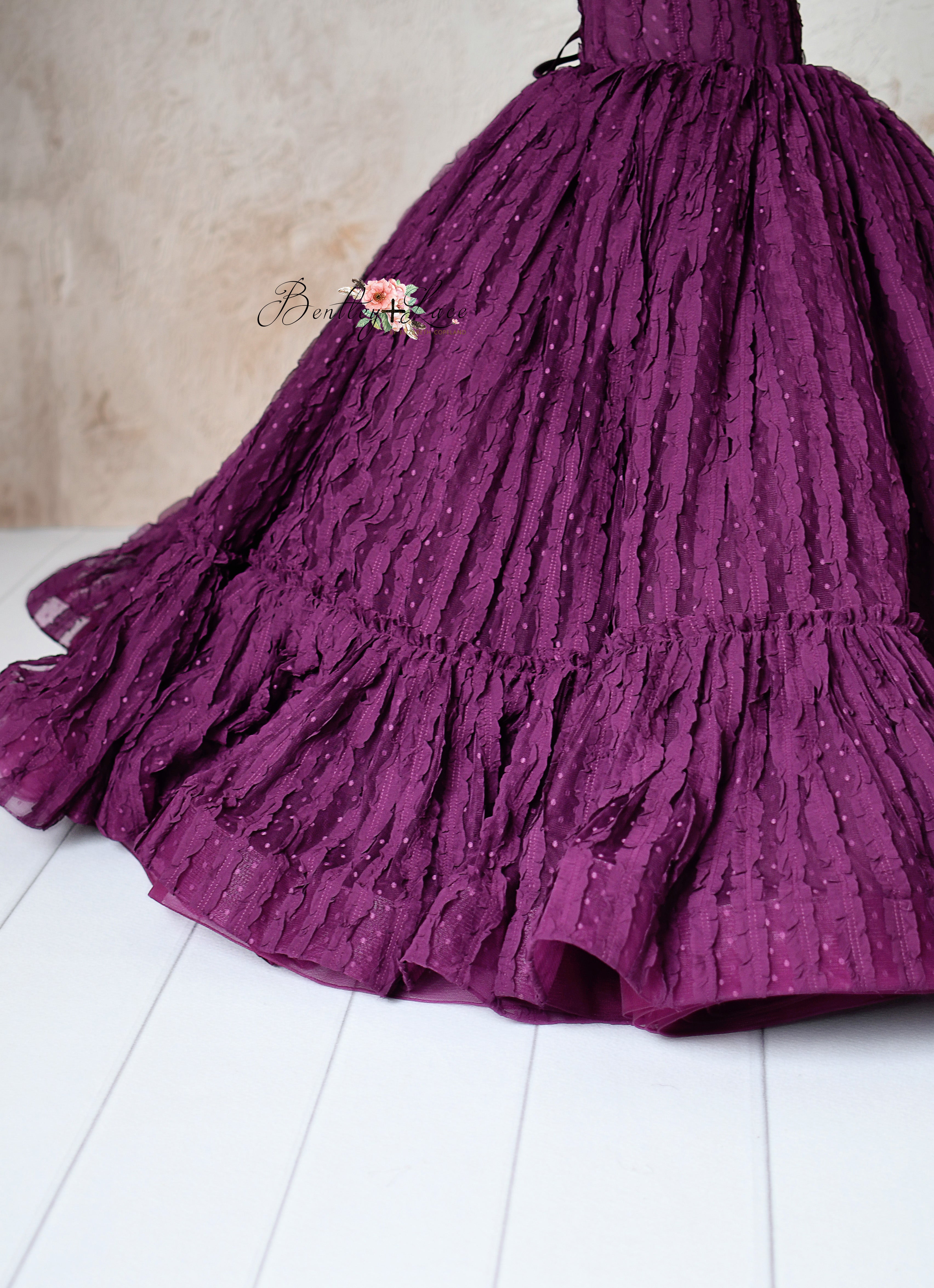 Elegant plum-colored gown with delicate ruffled lace details, designed for special occasions.
