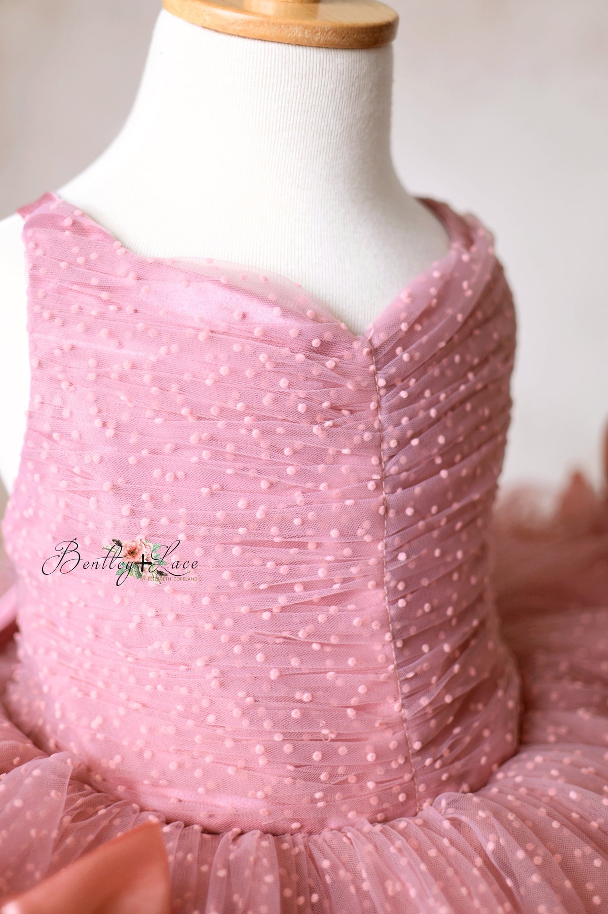 Intricate pink tulle dress with a pleated bodice and full skirt, perfect for special occasions.
