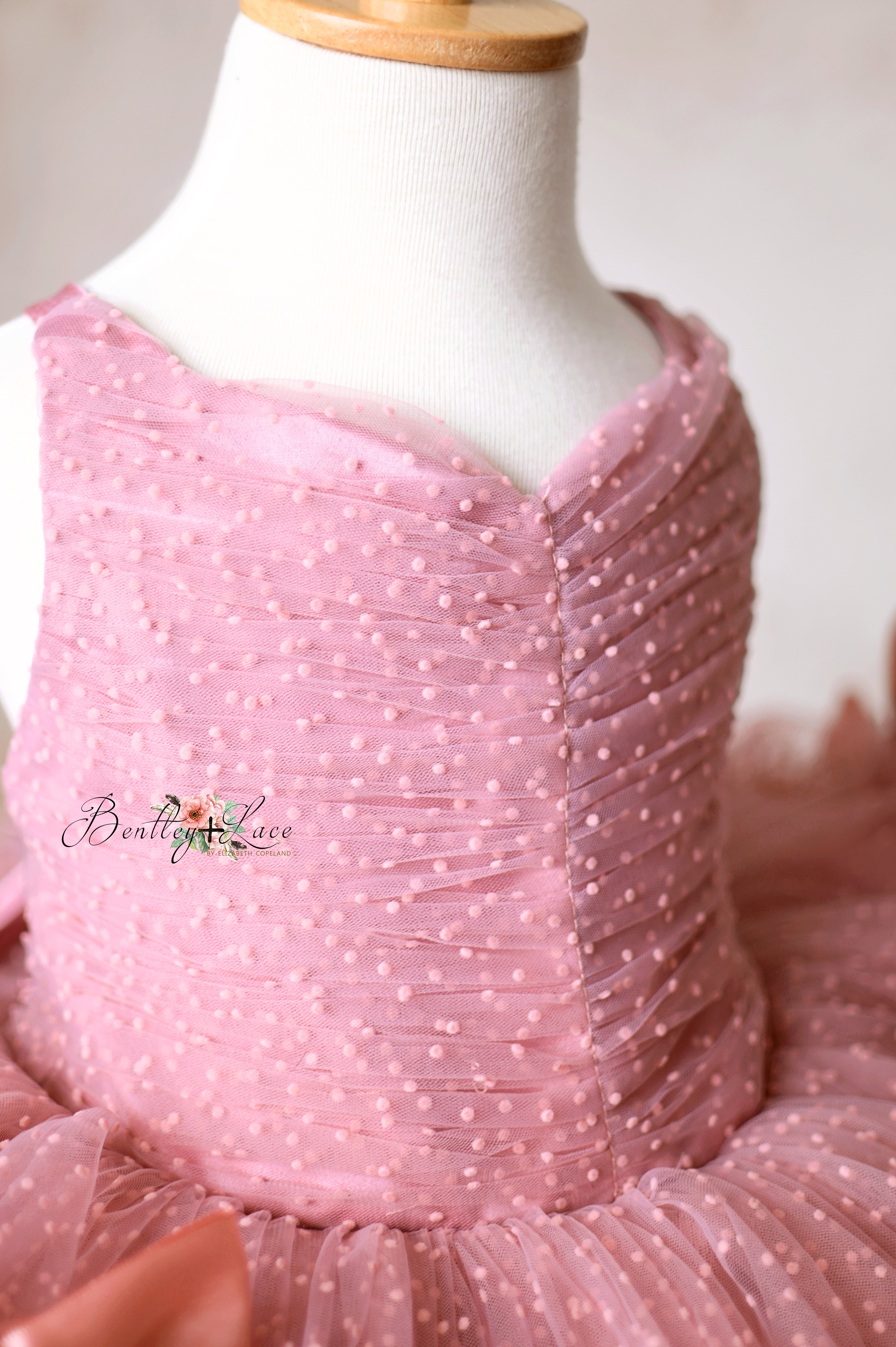 Intricate pink tulle dress with a pleated bodice and full skirt, perfect for special occasions.
