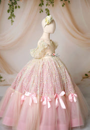 A floor-length pink gown with daisy sequin-embroidered lace and light pink bows, displayed on a mannequin.