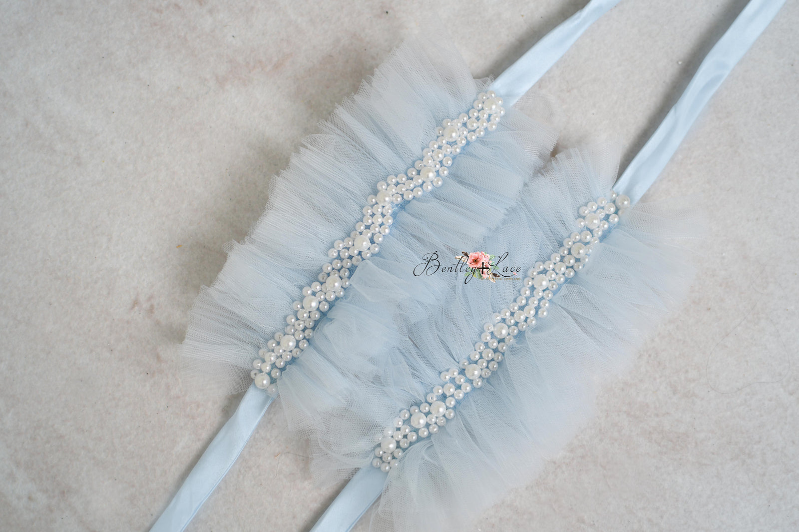 A pair of blue tulle wristlets with bead embellishments.