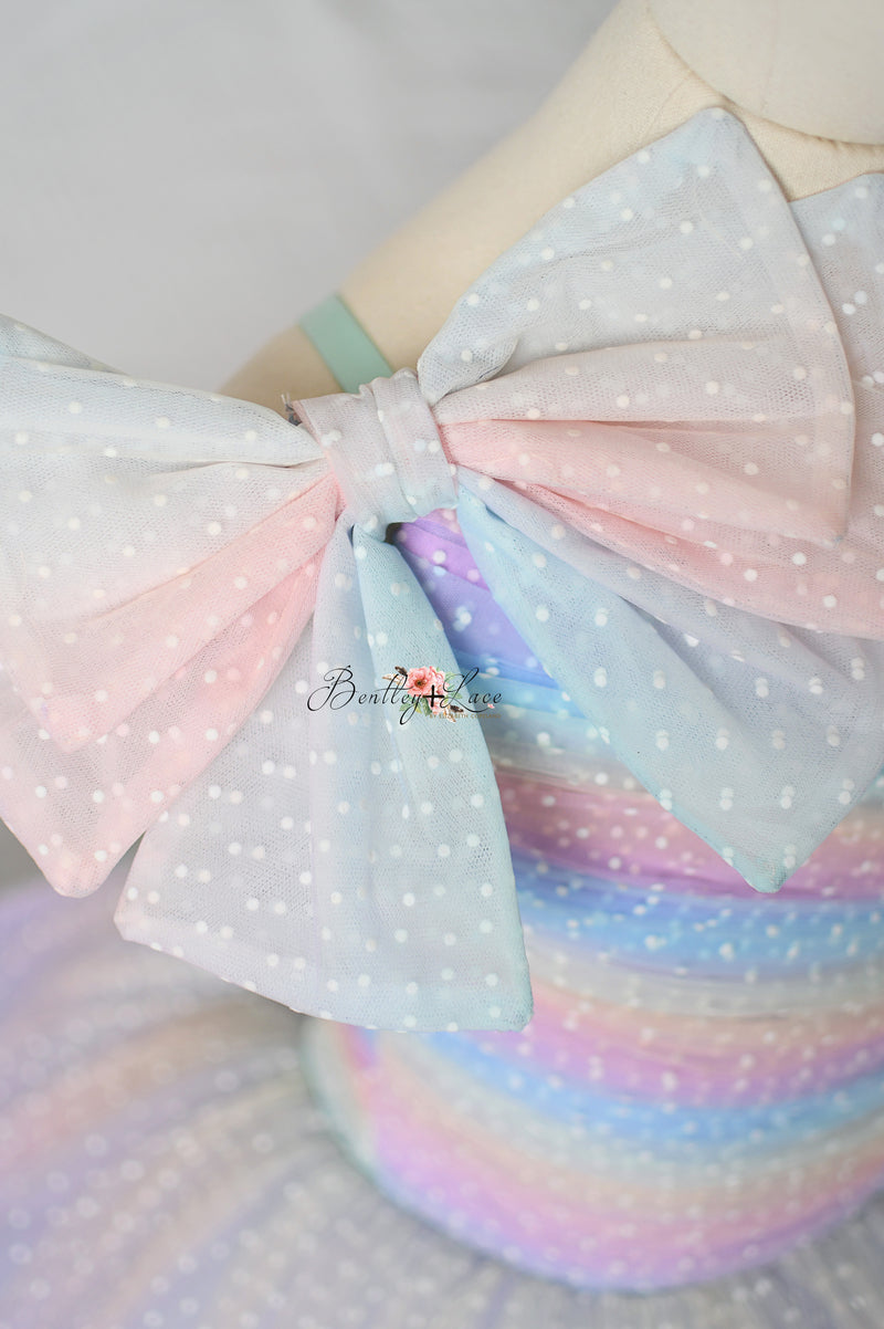 Flat lay of the Colorful Bliss Gown with matching detachable hair bow, showcasing the complete ensemble.

