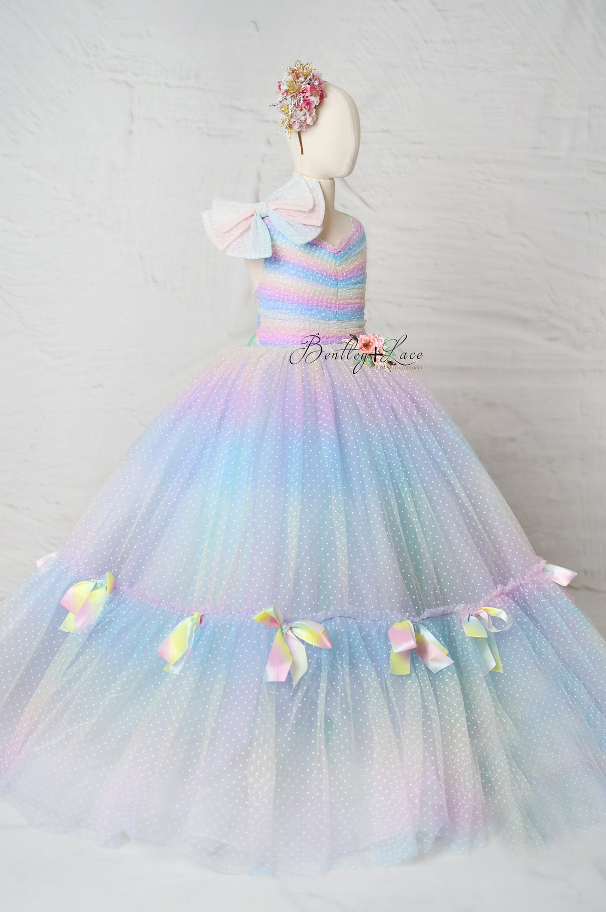 Close-up of the Colorful Bliss Gown’s rainbow swiss dot fabric, capturing its whimsical texture and vibrant, joyful color palette.

