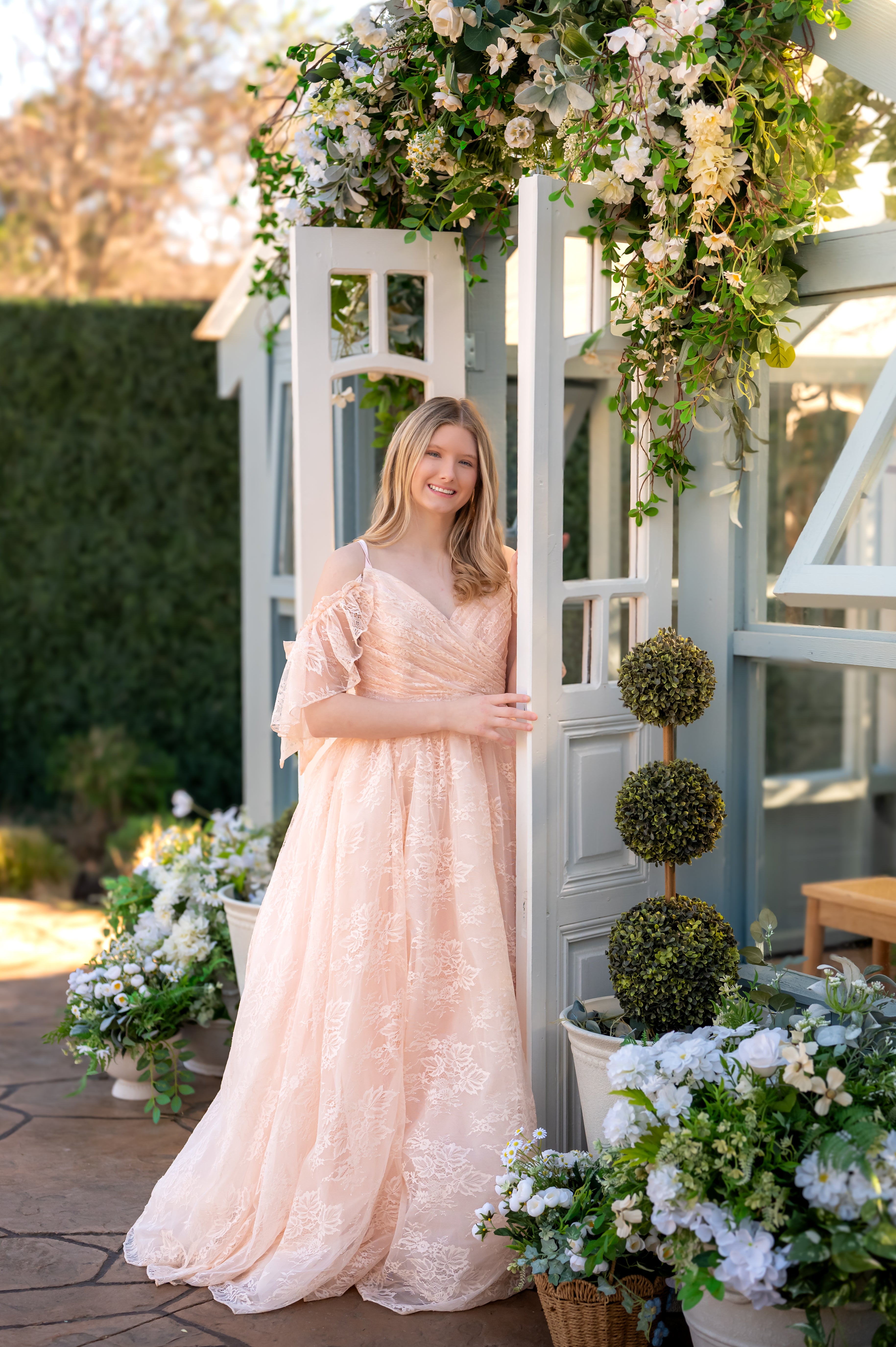 Woman in a peach dress standing in front of a floral archway