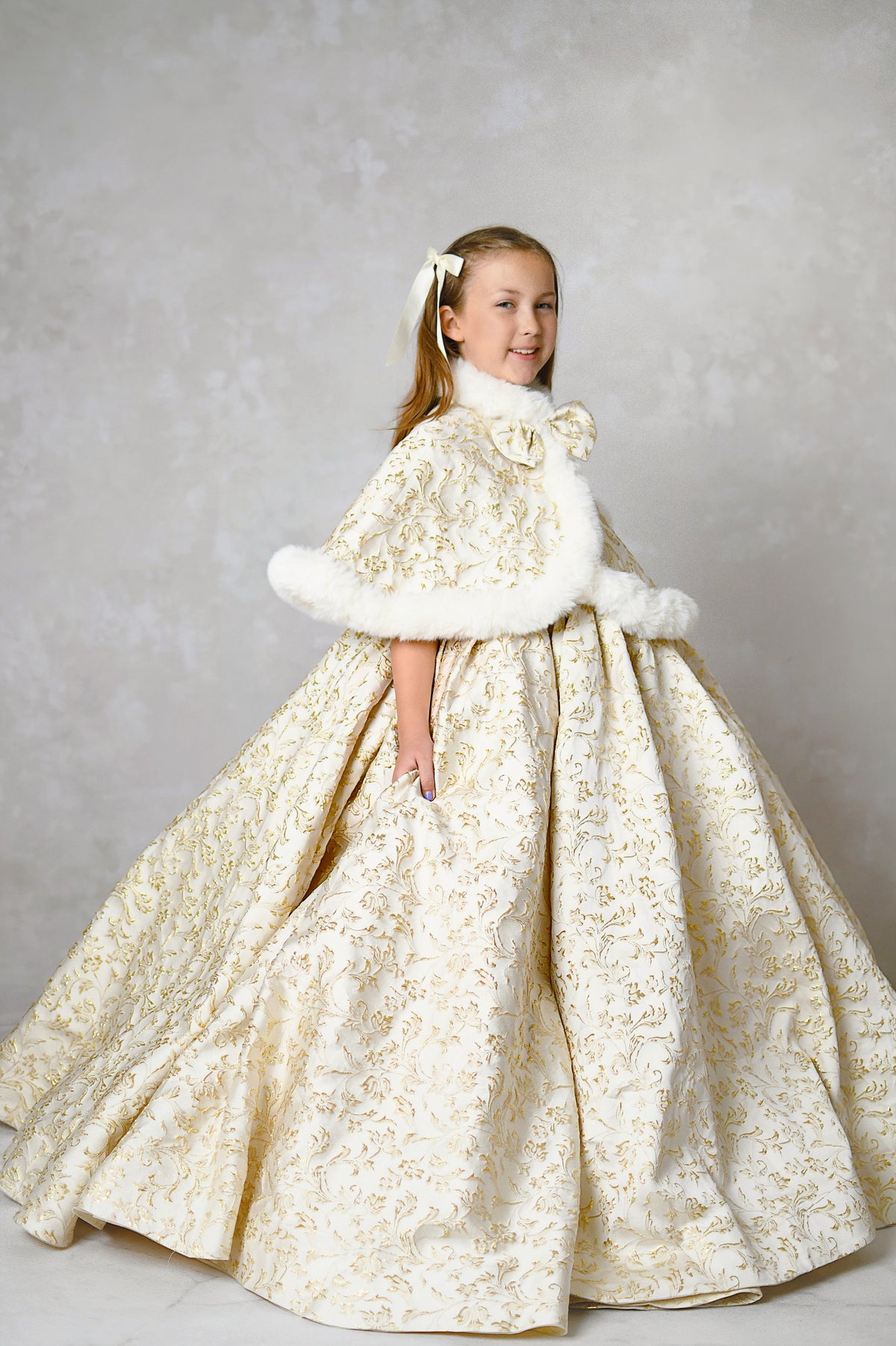 Christmas portrait of a girl in a luxurious custom gown with gold detailing and a floral headpiece.

