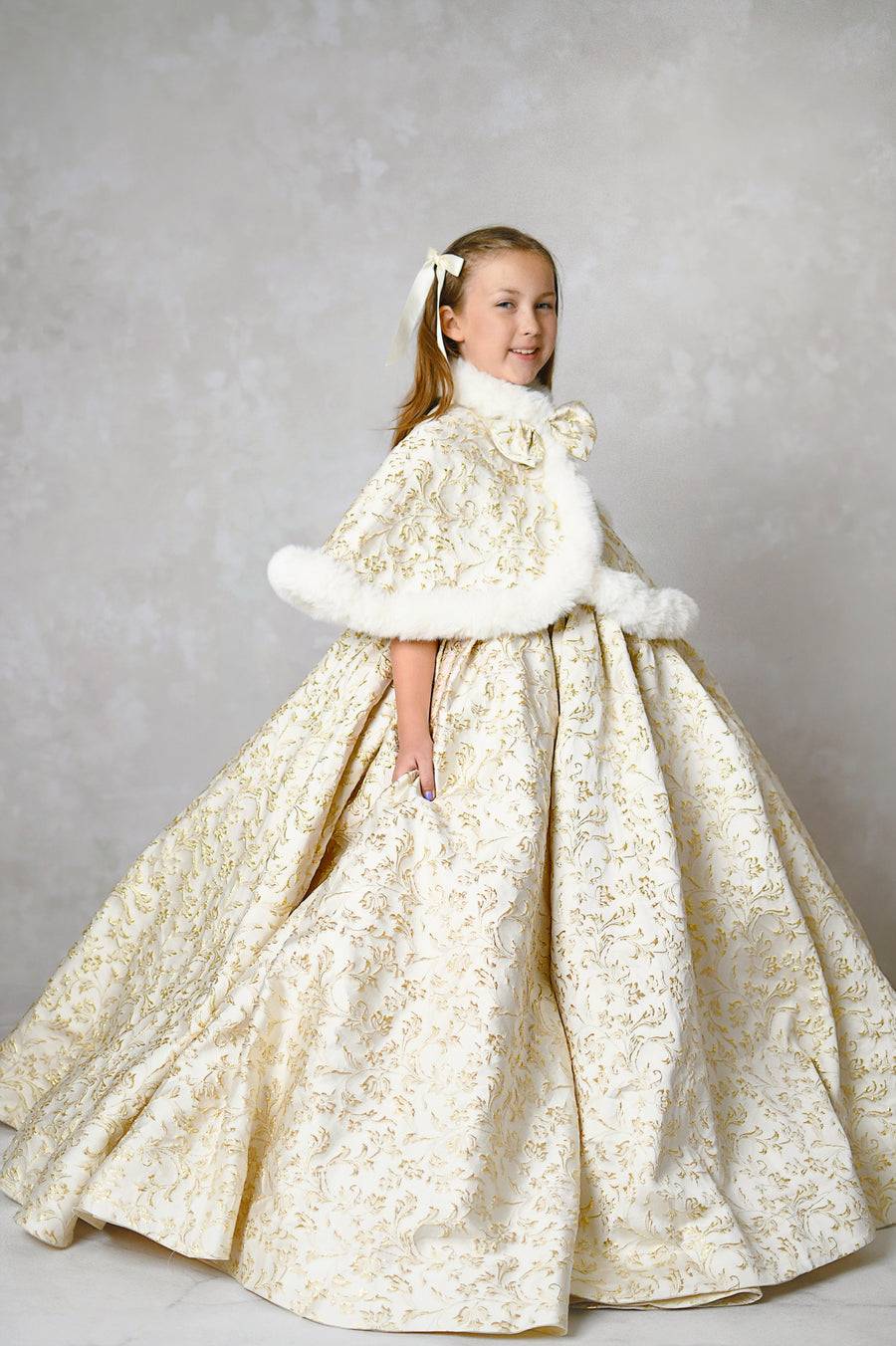 Christmas portrait of a girl in a luxurious custom gown with gold detailing and a floral headpiece.

