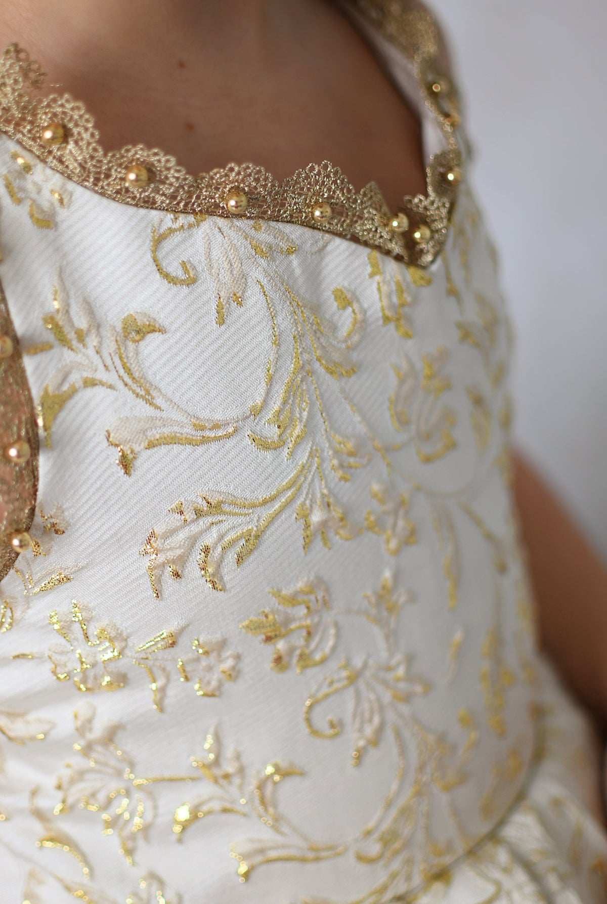 Girl in a Bentley + Lace couture holiday dress smiling in front of a dark wood door adorned with Christmas greenery and lights.

