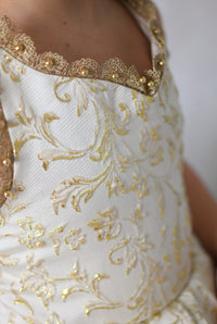 Girl in a Bentley + Lace couture holiday dress smiling in front of a dark wood door adorned with Christmas greenery and lights.

