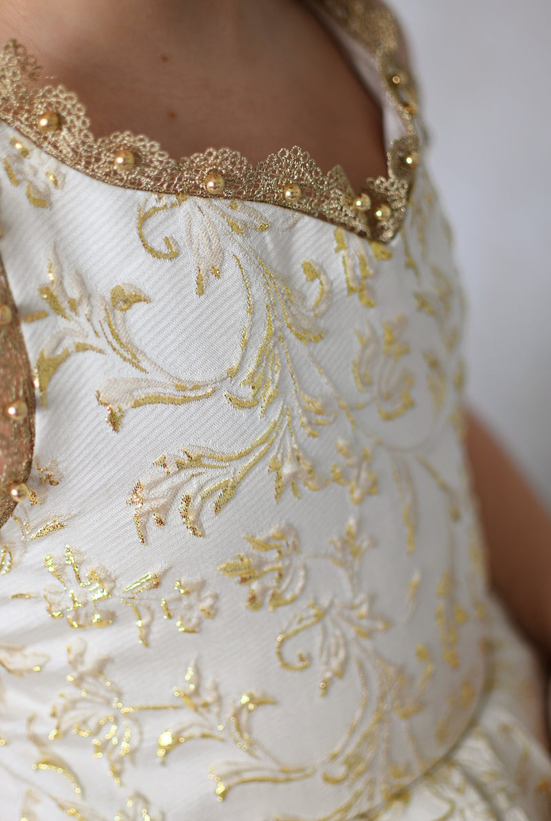 Girl in a Bentley + Lace couture holiday dress smiling in front of a dark wood door adorned with Christmas greenery and lights.


