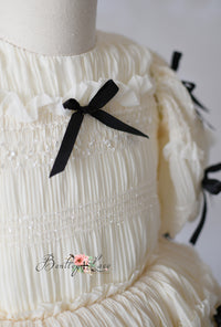 Frosted Ribboncake dress by Bentley and Lace, featuring soft tulle, smocking, and elegant black bow details.

