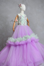 A floor-length gown with a floral pattern on the bodice and a solid purple tulle skirt with a petticoat underneath. The dress features shoulder ties and an elastic waist.
