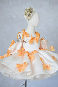 “Ivory satin luxury dress for girls with clementine bow detailing”

