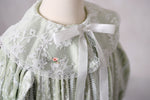 Front view of Eleanor’s Dream sage green gown highlighting the faux button closure and timeless design details.

