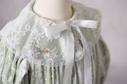 Front view of Eleanor’s Dream sage green gown highlighting the faux button closure and timeless design details.

