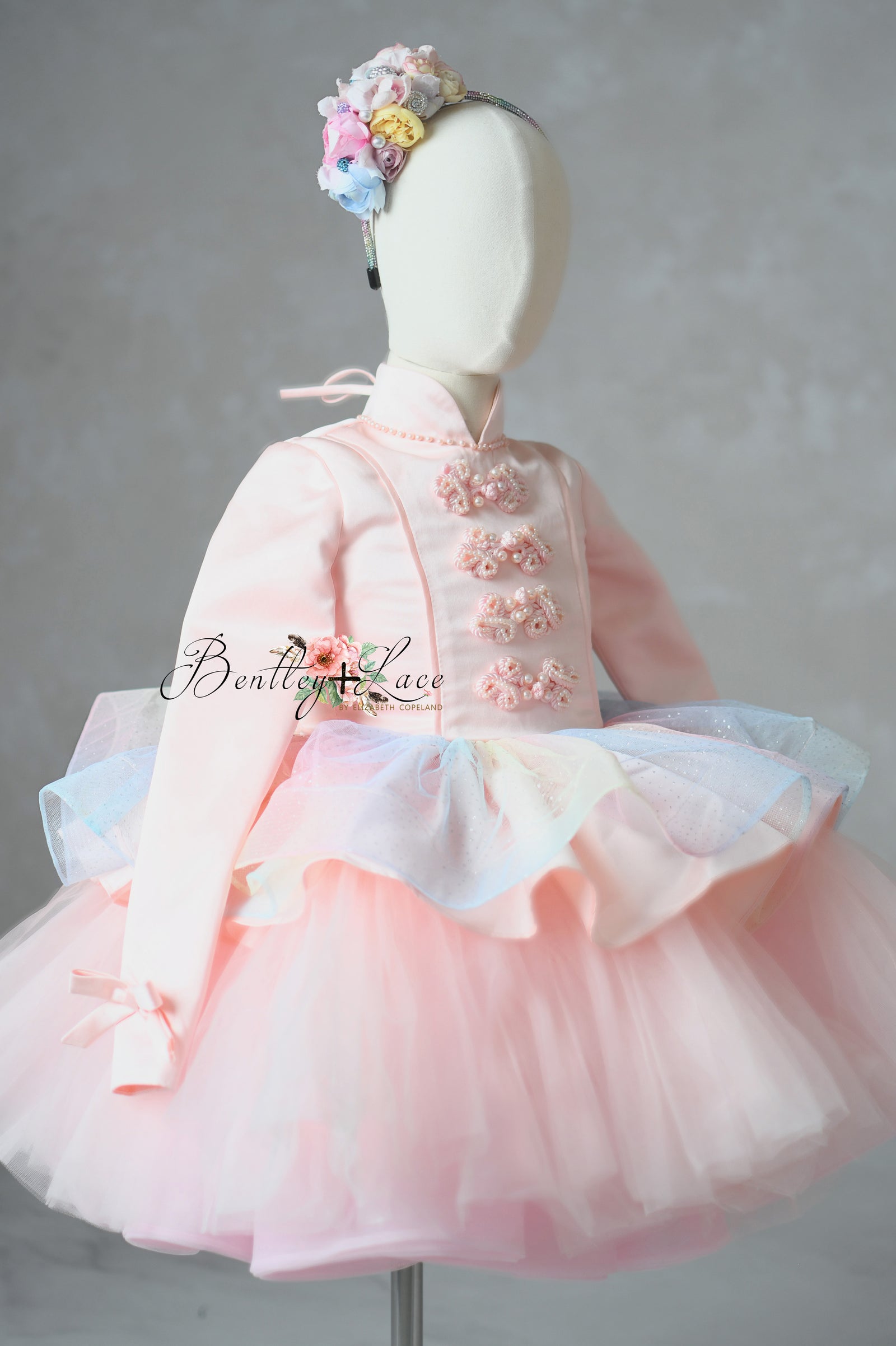 Pink traditional dress with floral headband on a mannequin against a gray background