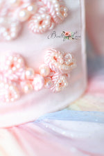 Close-up of decorative flowers with pearls on a textured surface, featuring the brand 'Bentilly Lace'.
