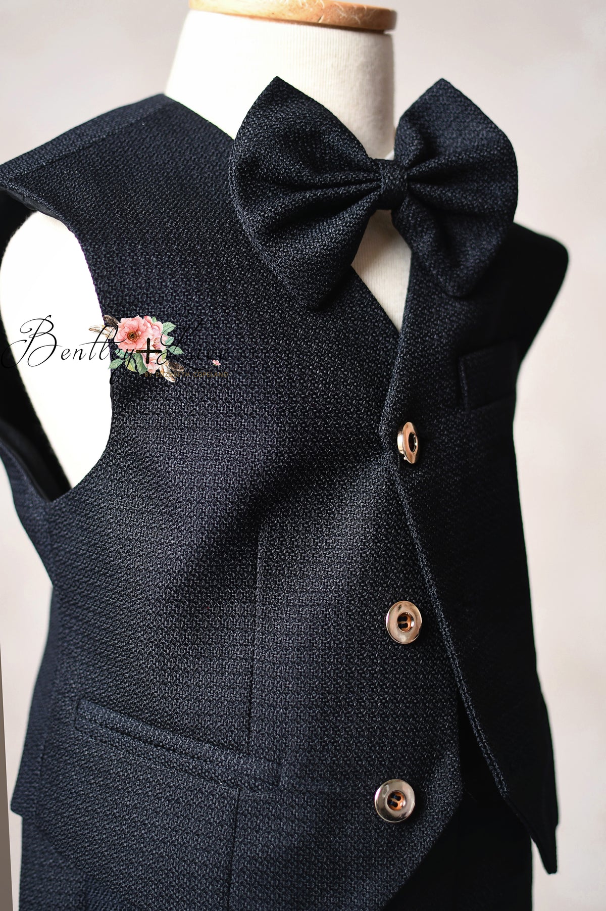 Black vest with a large bow tie on a mannequin against a white background