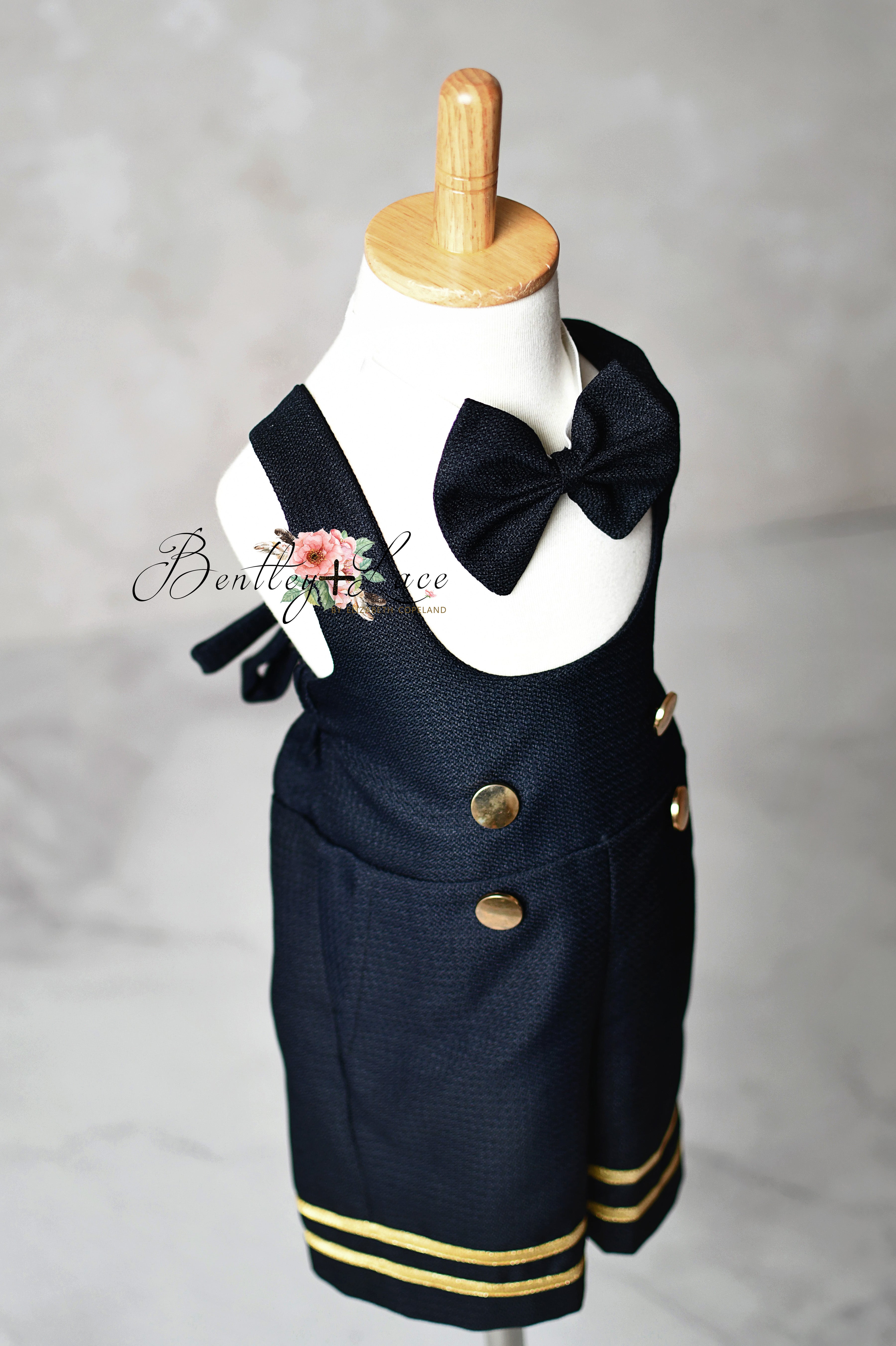 Navy blue children's outfit with gold buttons on a mannequin against a gray background.
