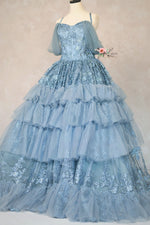 Blue lace gown on a mannequin against a plain background