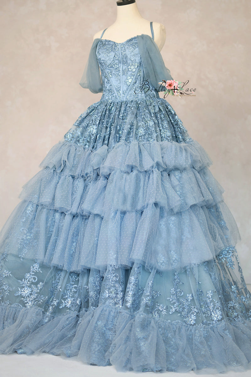 Blue lace gown on a mannequin against a plain background