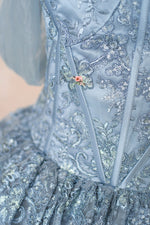 Close-up of a blue embroidered garment with floral details.
