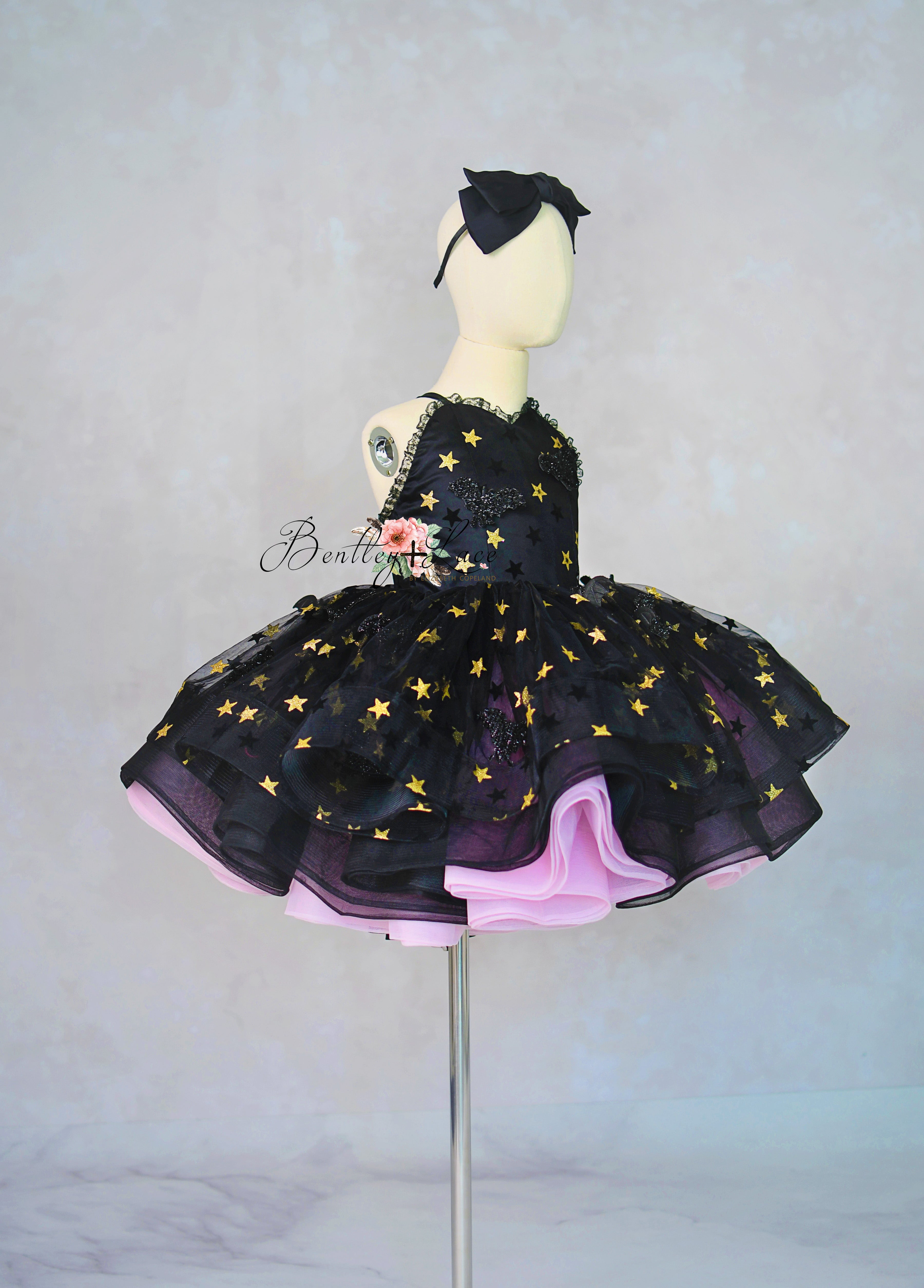 Black dress with star patterns on a mannequin against a gray background