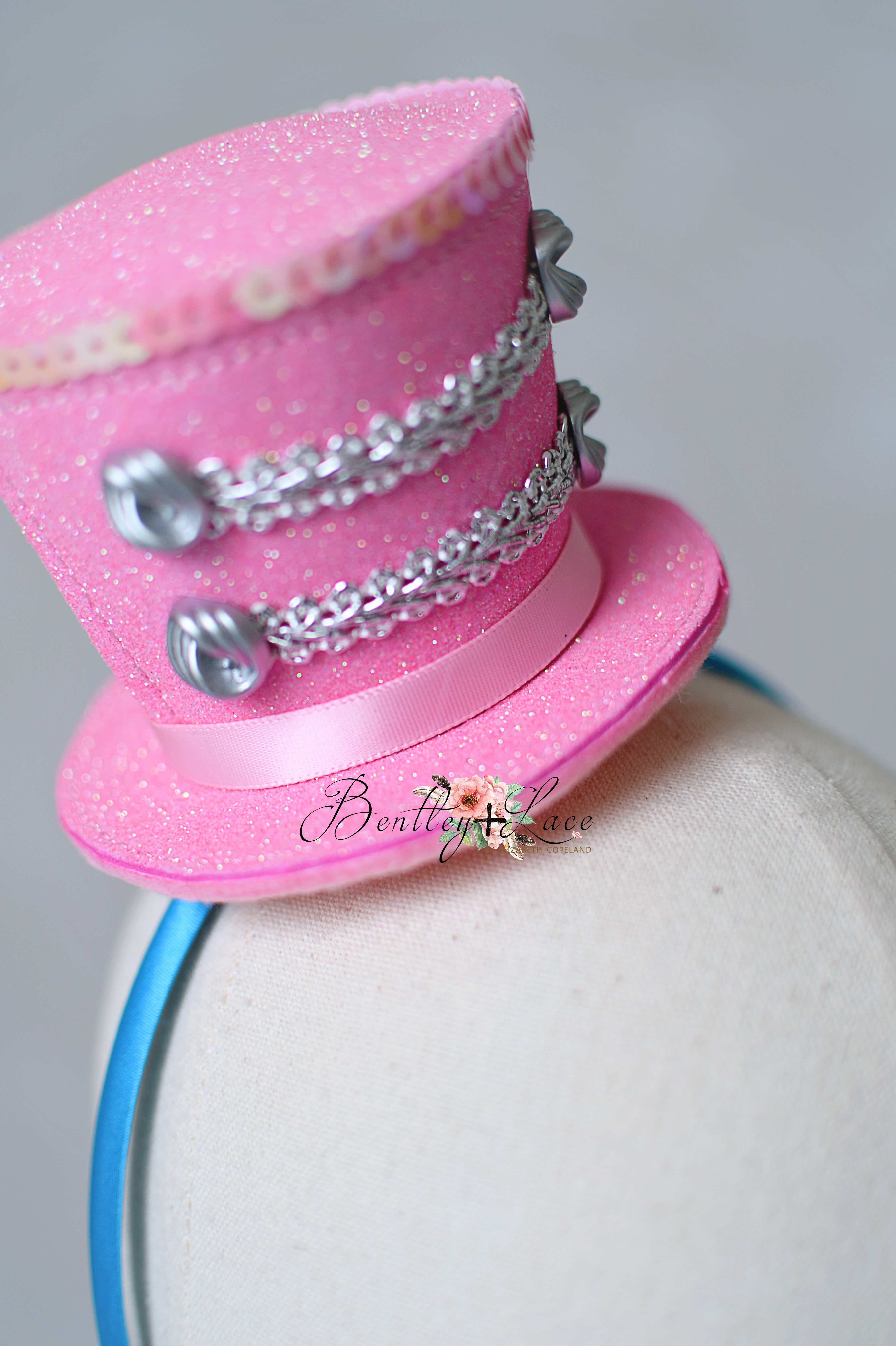 Pink decorative hat with silver chains on a mannequin head against a white background