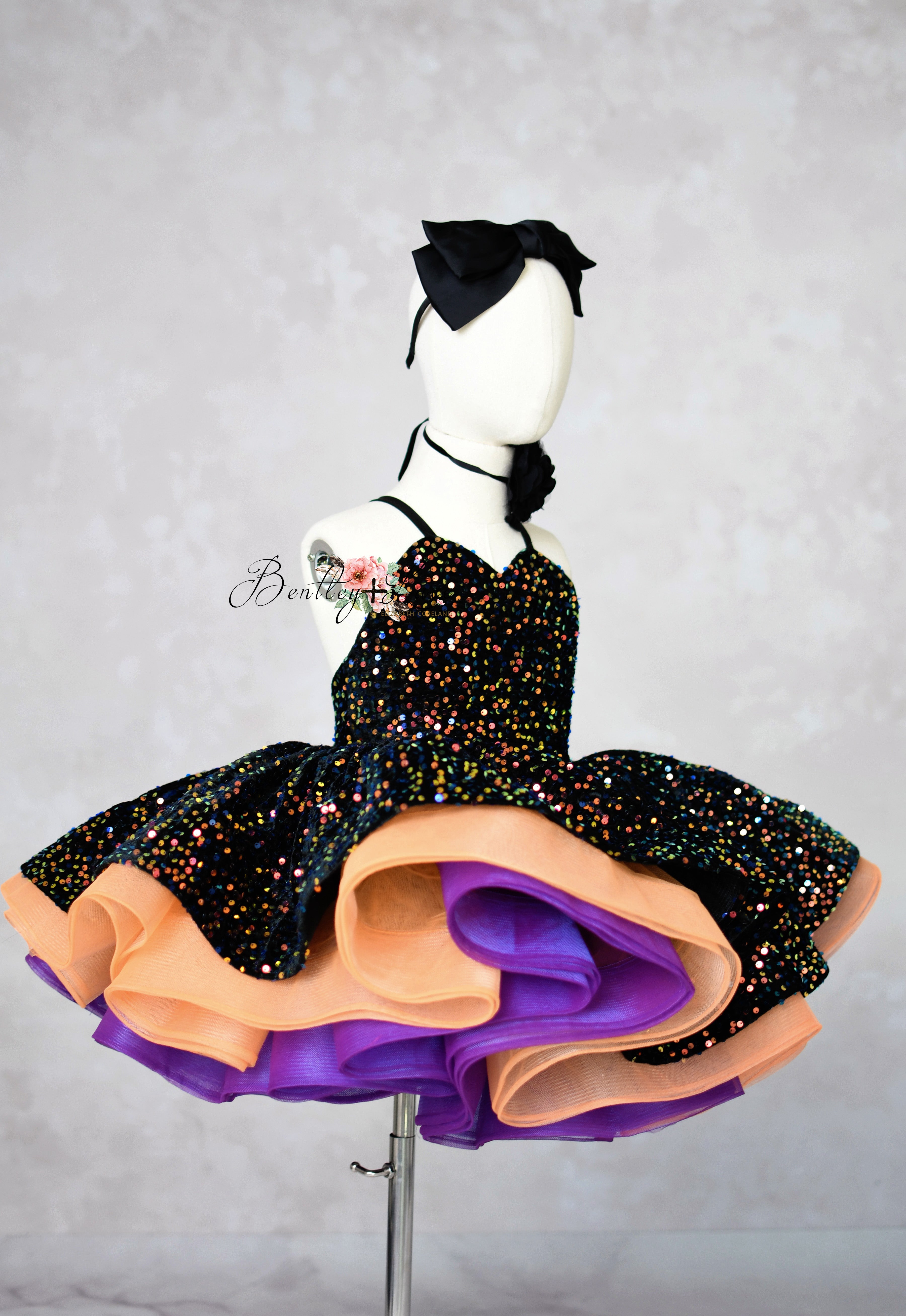 Mannequin wearing a black dress with colorful layers on a gray background