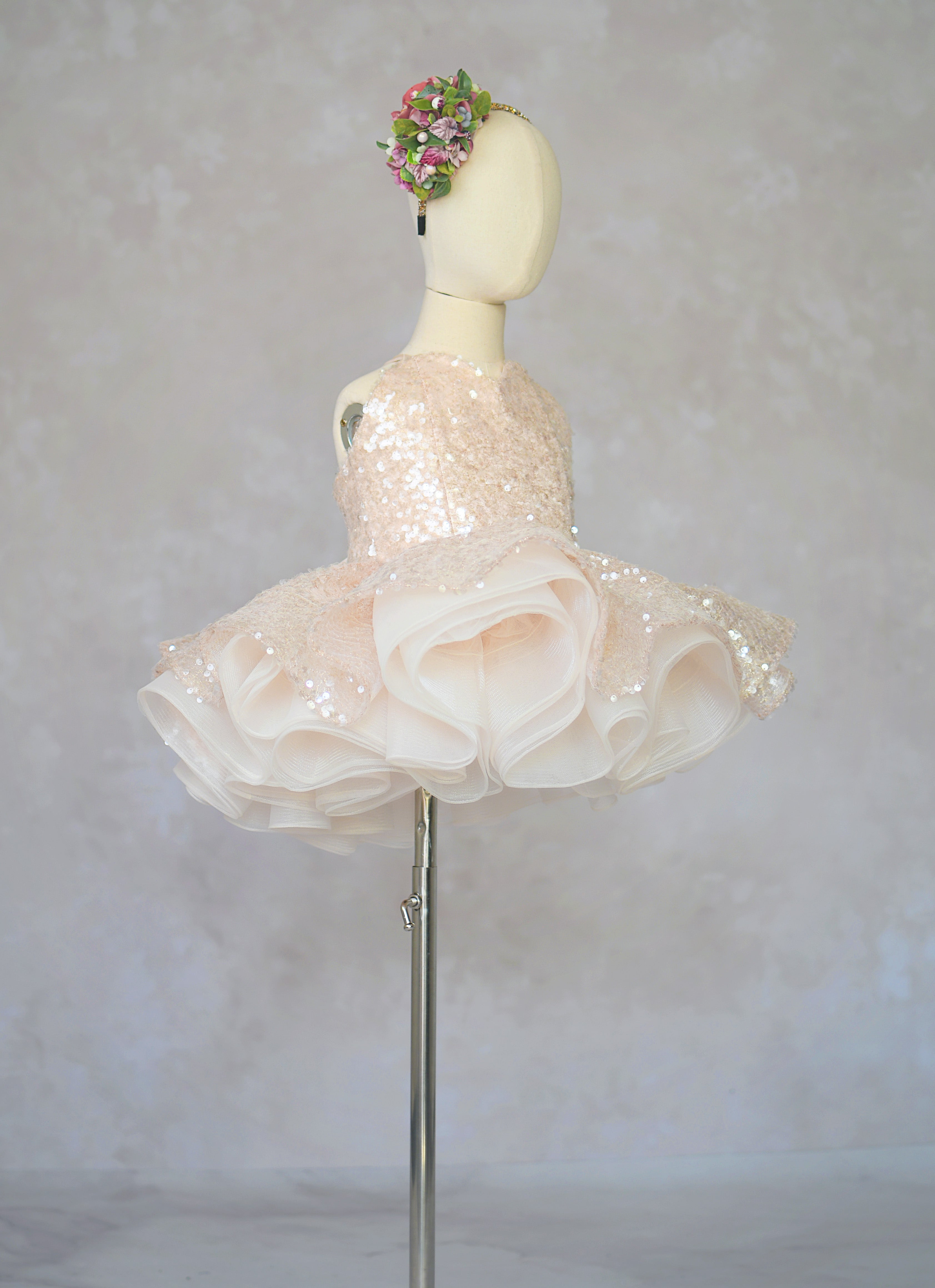 Mannequin wearing a floral headpiece and a decorative dress with a white background