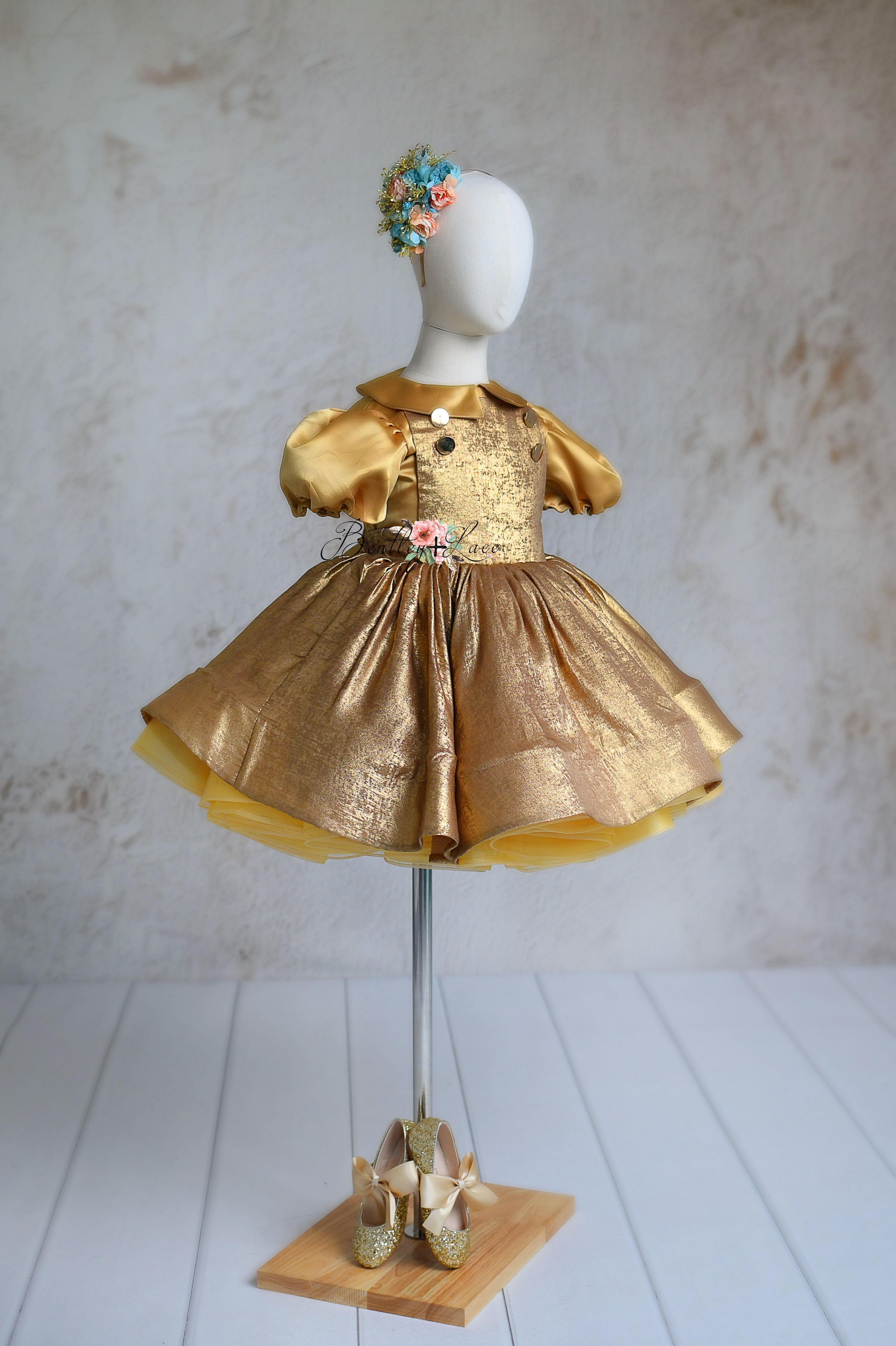 Golden Belle dress with shimmering gold fabric and floral headband accessory.