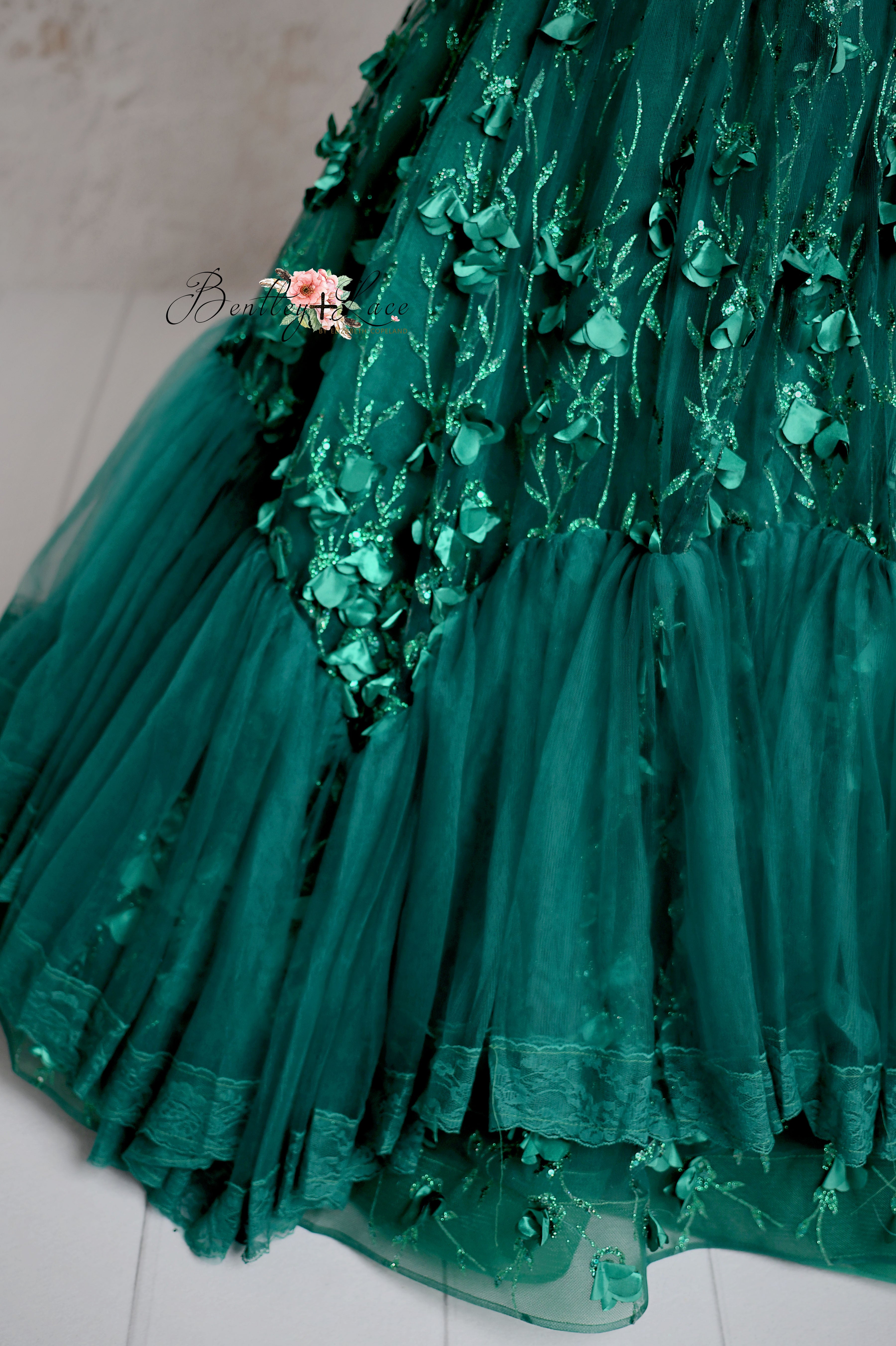 Detailed view of a luxurious green dress adorned with intricate floral appliqués