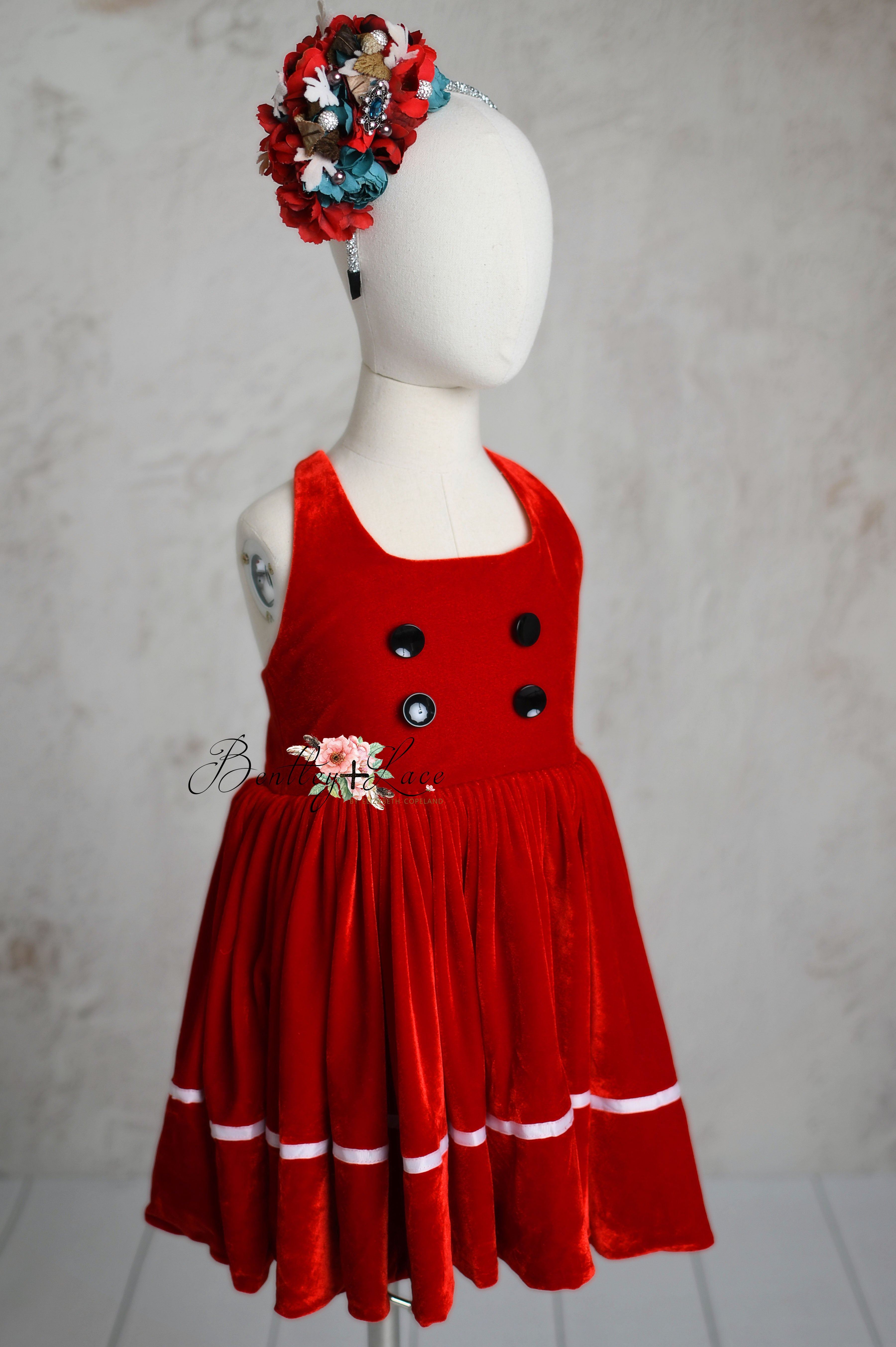 front view of a child's Santa's Helper red velvet apron dress with a festive headband, perfect for holiday celebrations.